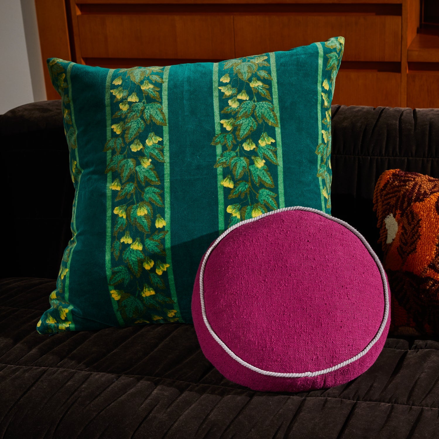 Agata Velvet Cushion styled on dark charcoal sofa with magenta round cushion in modern living room