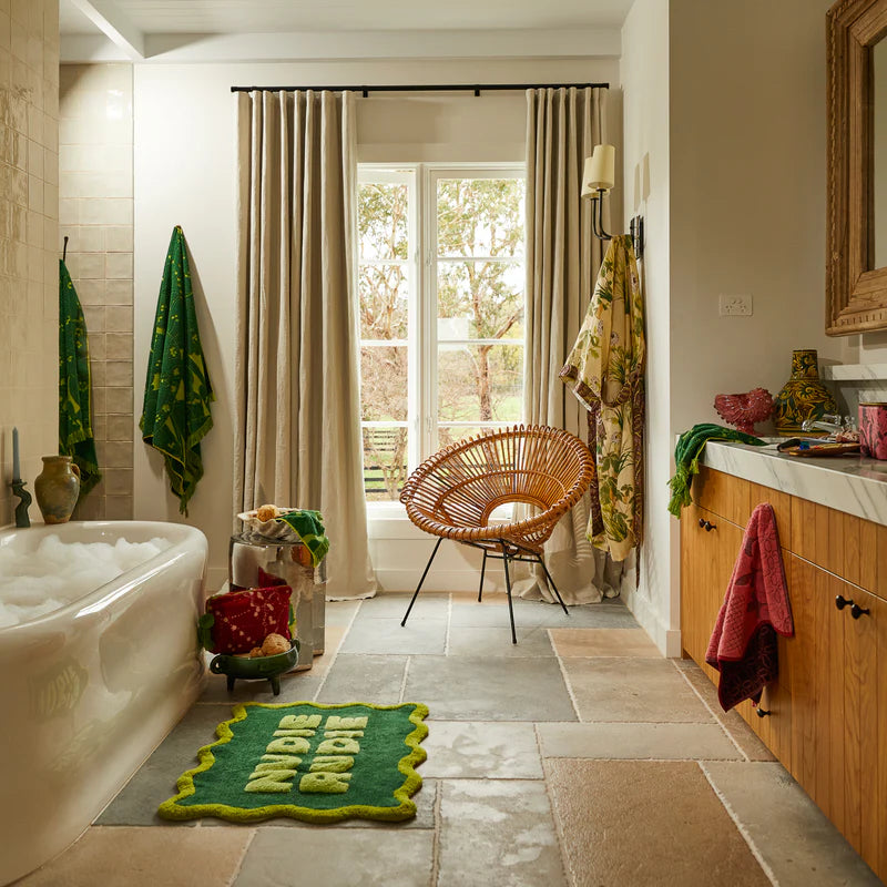 bathroom with Amalie Nudie Bath Mat - Kelp by Sage & Clare - dark green bath mat with light green "nudie rudie" text and wavy light green border