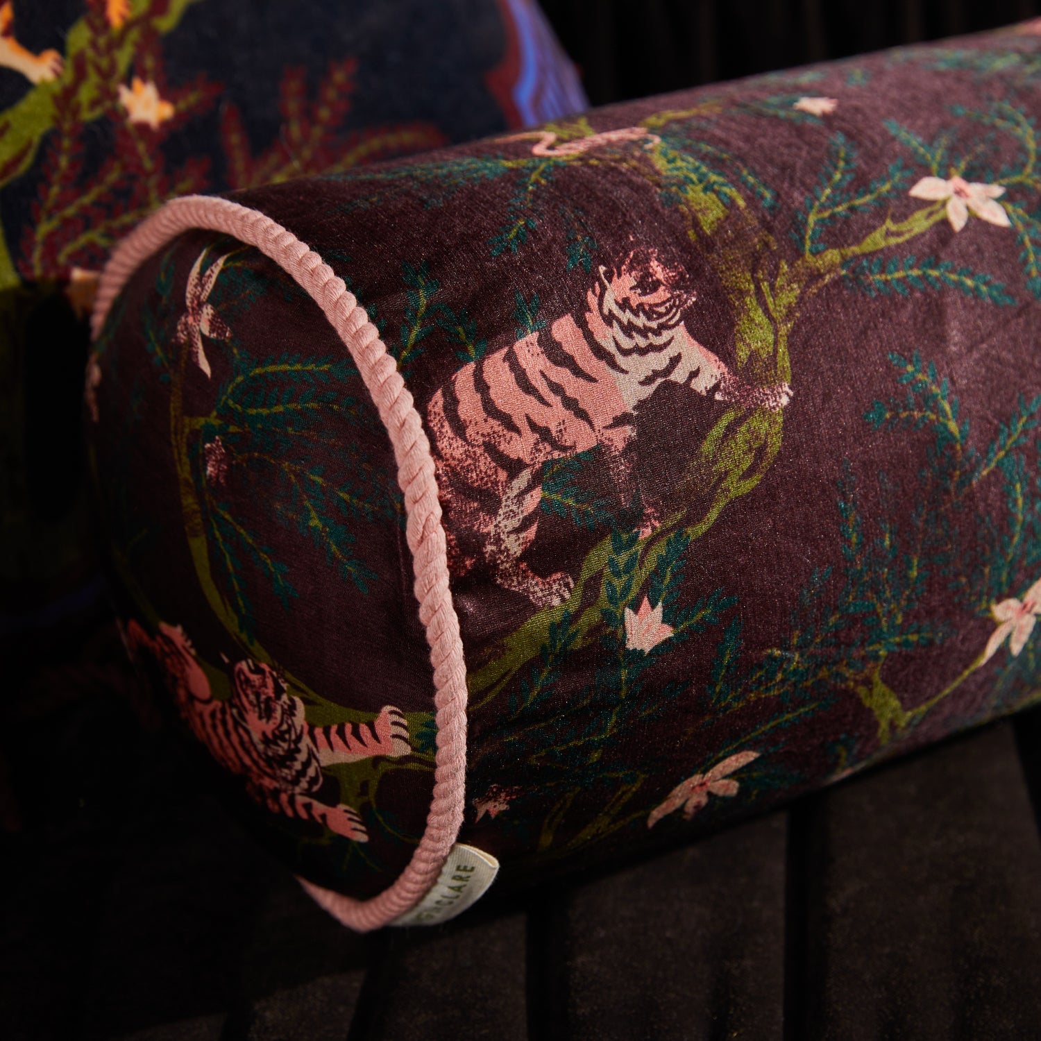 Close-up detail of pink tiger motif and floral pattern on rosewood linen silk Andrea Bolster Cushion