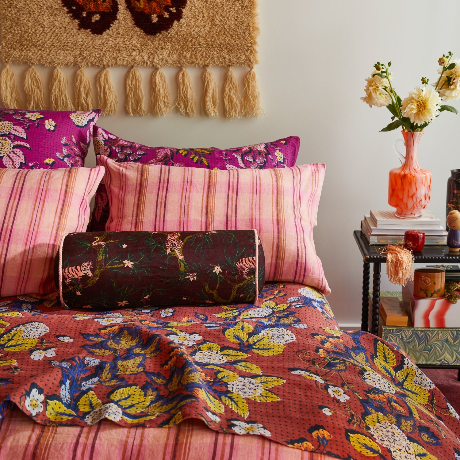 Andrea Bolster Cushion in Rosewood styled on bedroom with colorful bedding and bohemian decor
