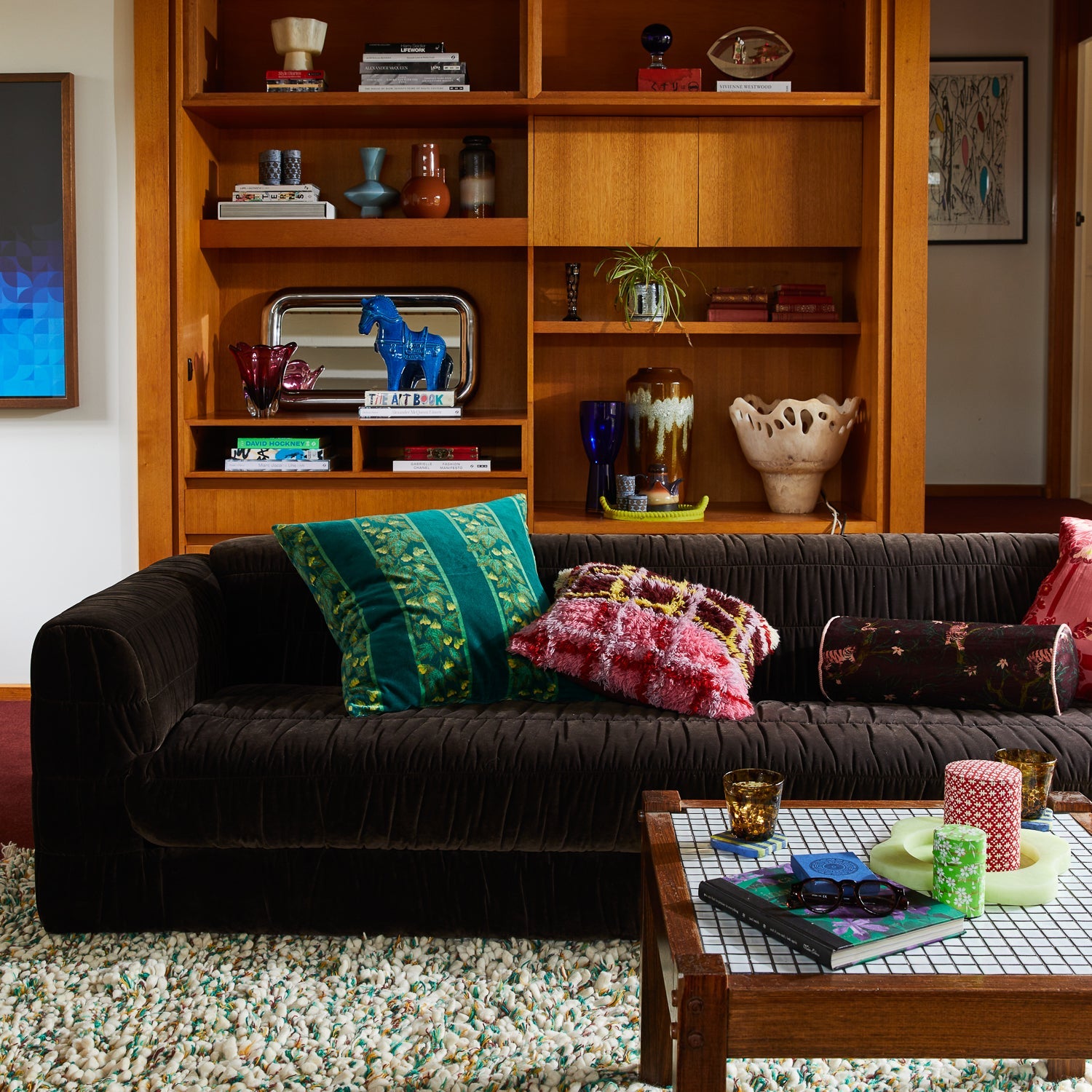 Living room styling of Andrea Bolster Cushion on dark sofa with mid-century modern shelving
