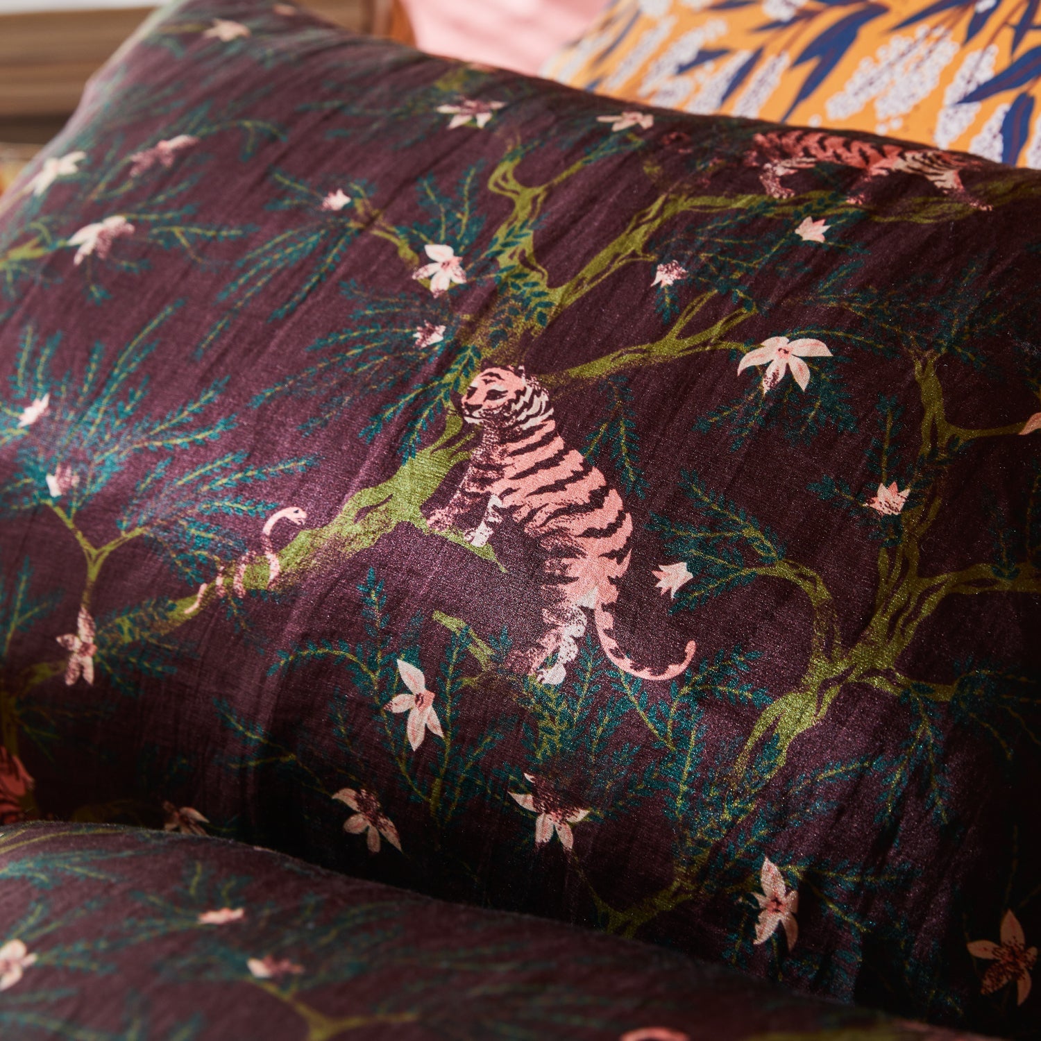 Close-up detail of tiger motif and pink florals on rosewood linen-silk fabric showing lustrous texture