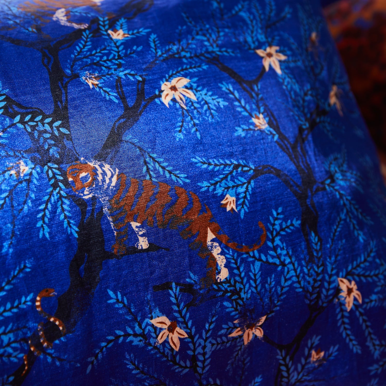 Close-up of tiger and botanical print detail on ultramarine linen-silk pillowcase fabric