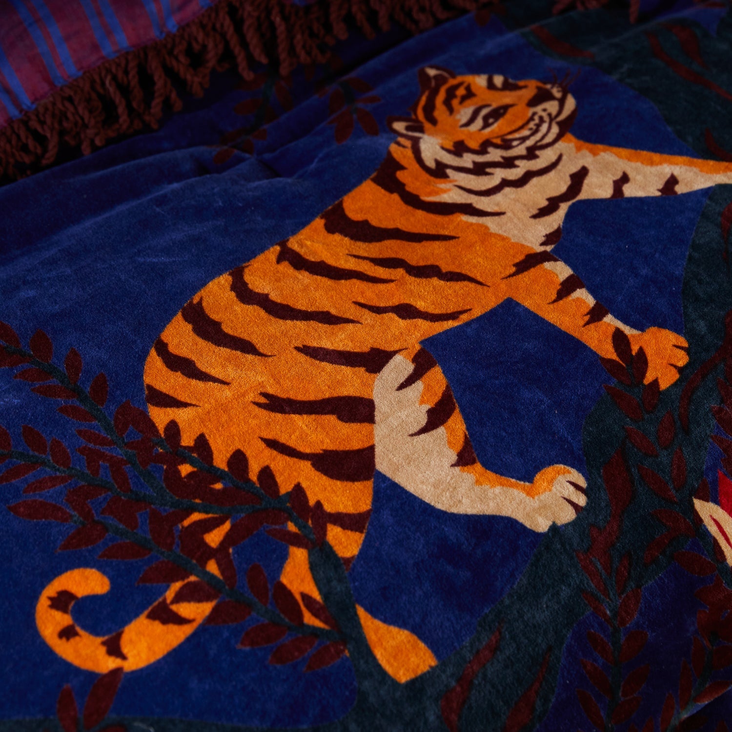 Side view of Andrea Velvet Bedcover showing burgundy striped reverse pattern and decorative fringe edging