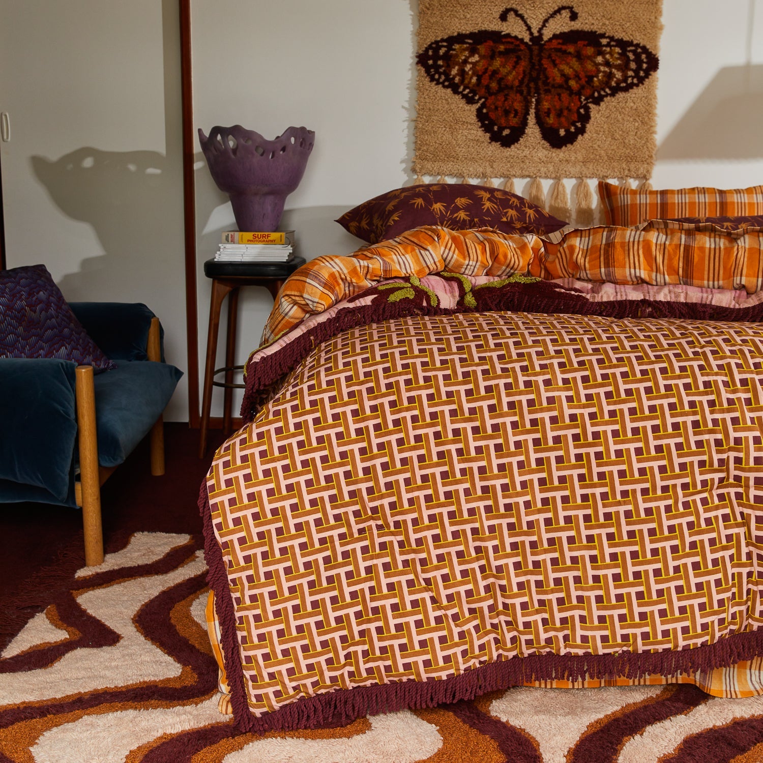 Side angle view of Aneta Tufted Blanket on bed showing pink palm motifs and layered textile styling
