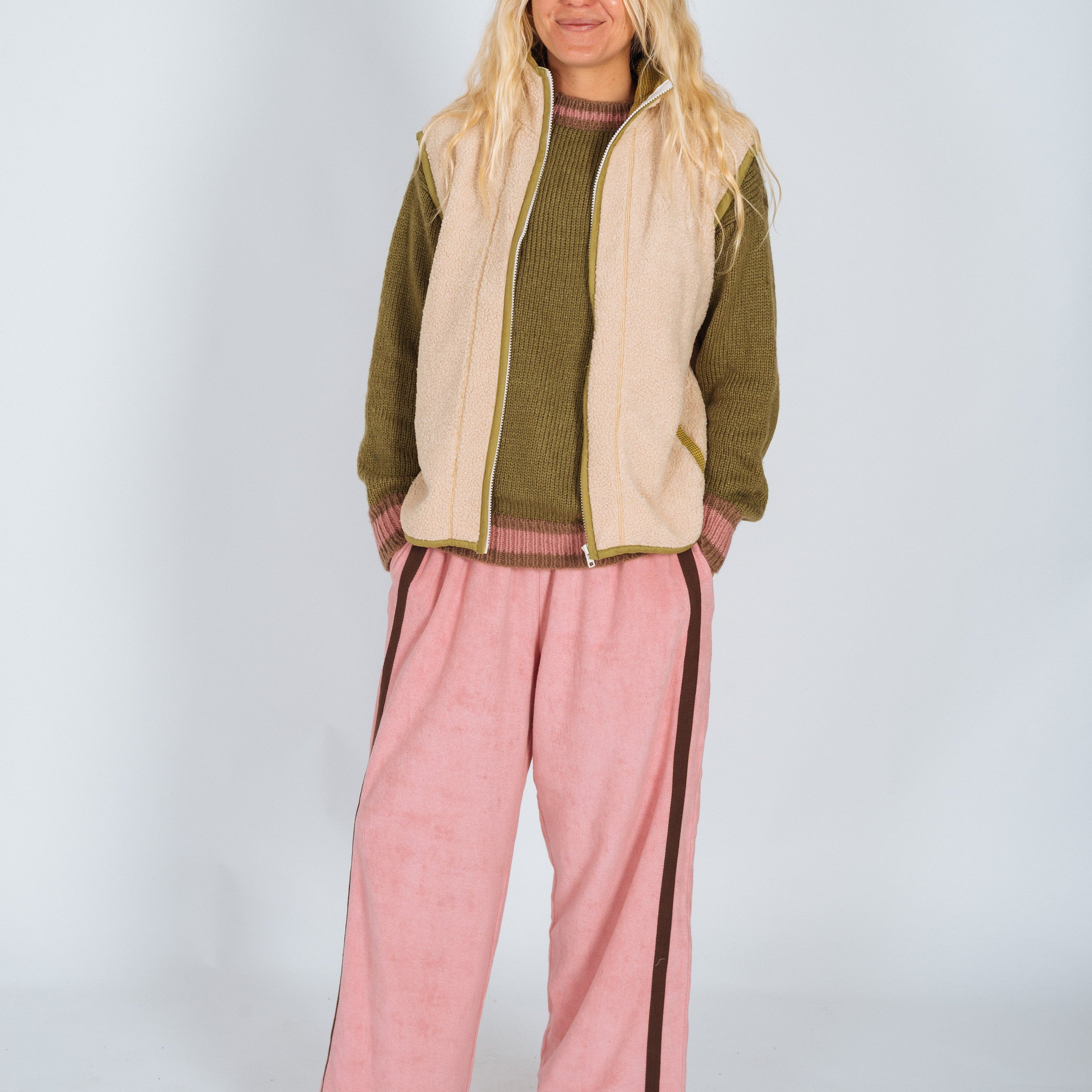 Front view of Atmosea Après Surf Panel Pant in blush pink worn with olive sweater and cream vest
