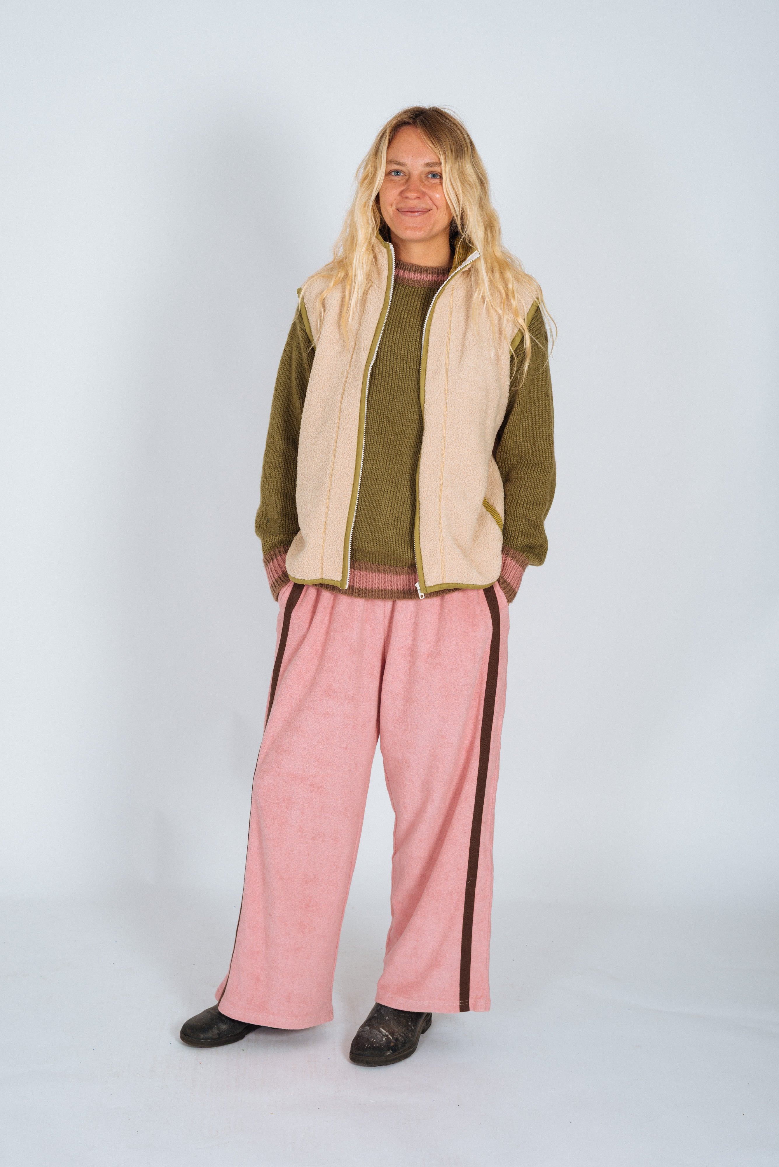 Front view of Atmosea Après Surf Panel Pant in blush pink worn with olive sweater and cream vest