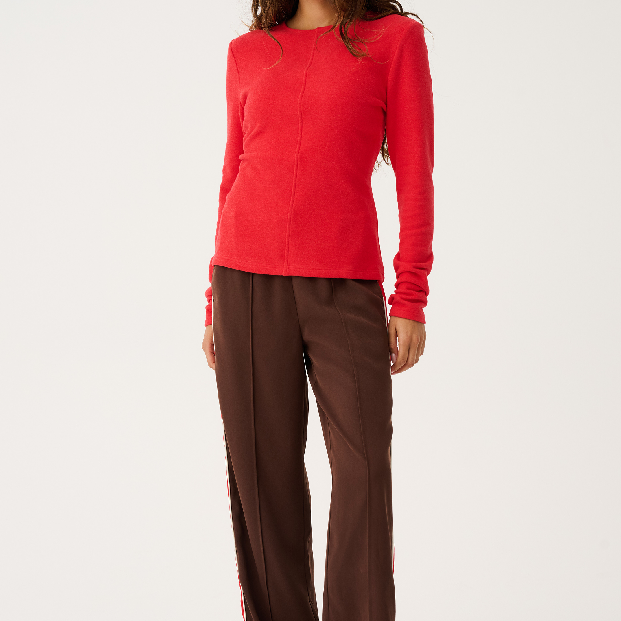 Full body front view of red Aspyn Top Siren styled with brown trousers showing complete outfit