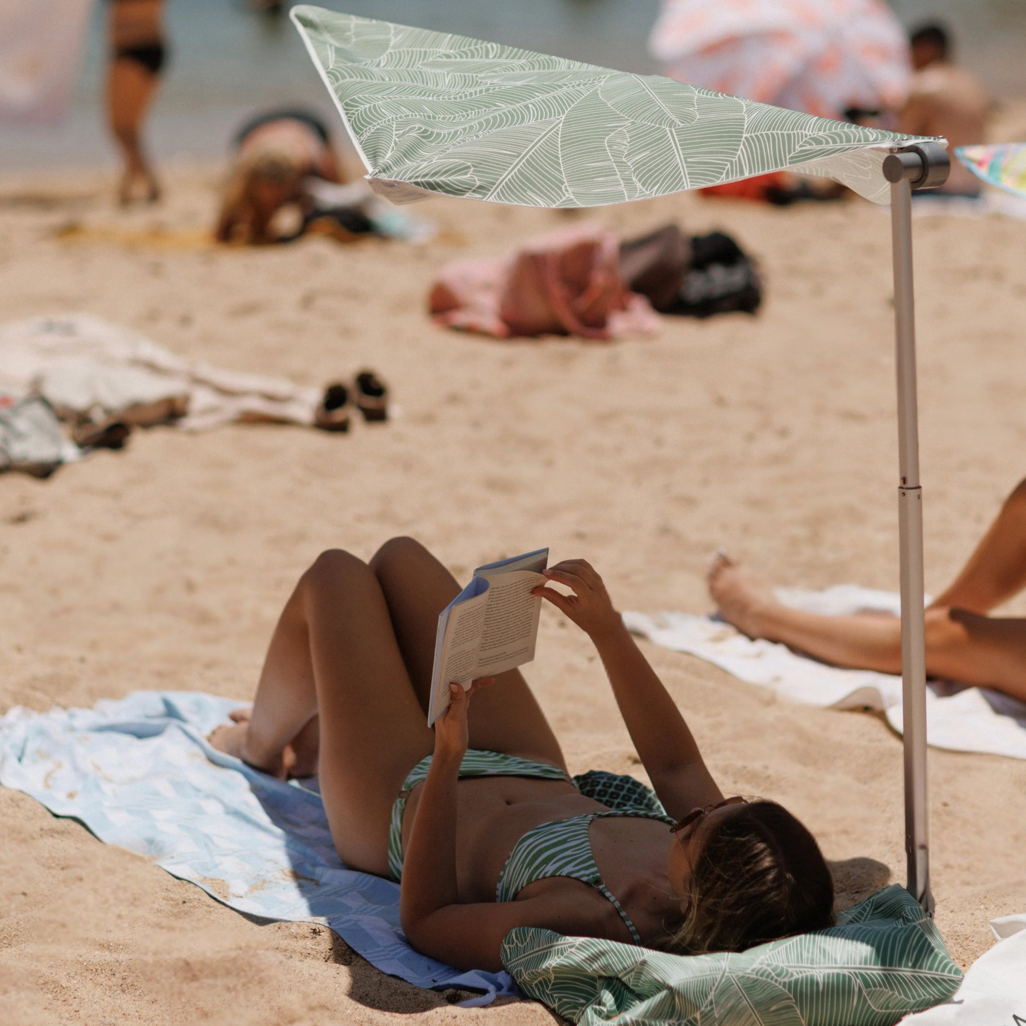Lady laying under best compact beach umbrella - Tranquil swim shady