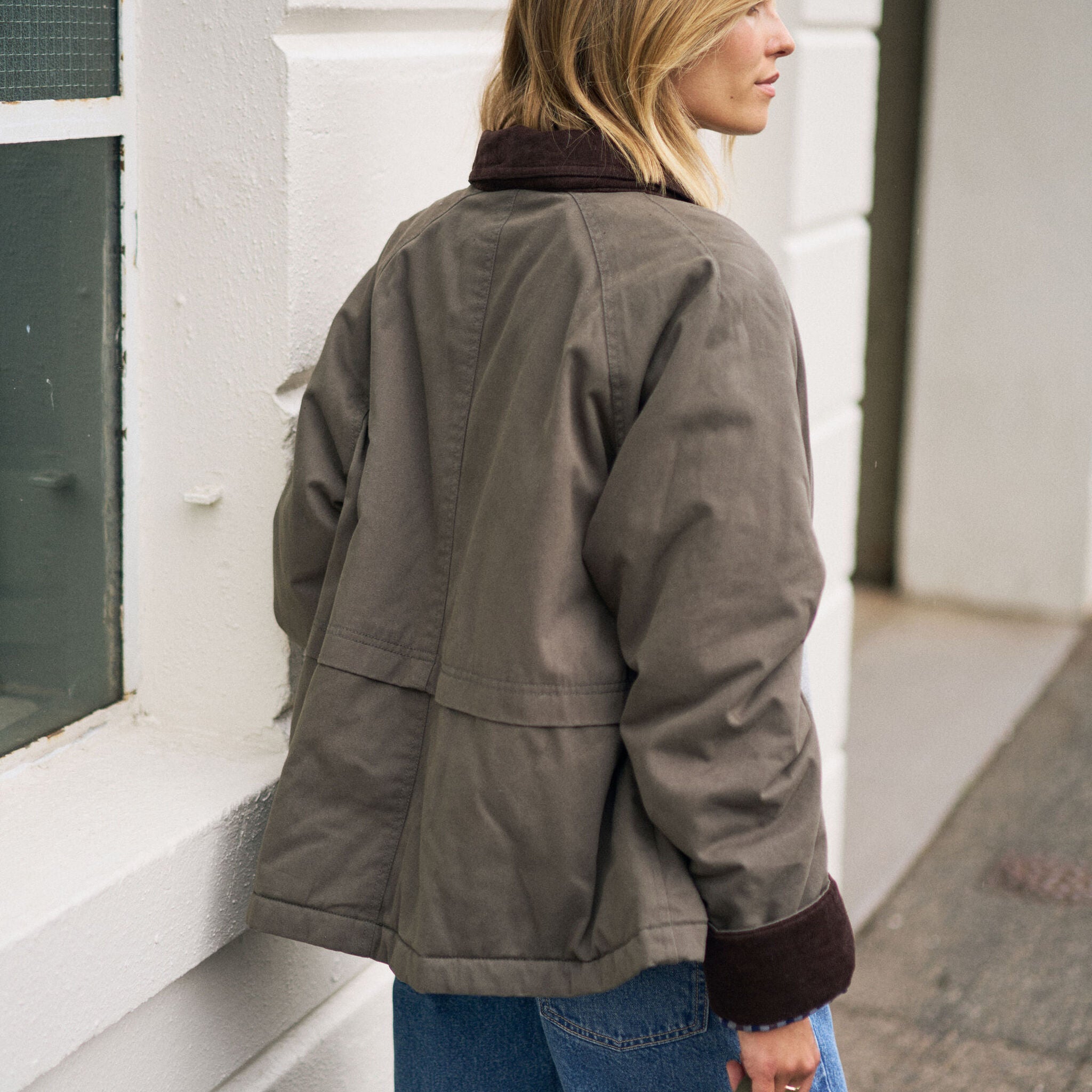 Back angle view of moss green barn jacket with corduroy collar and relaxed silhouette