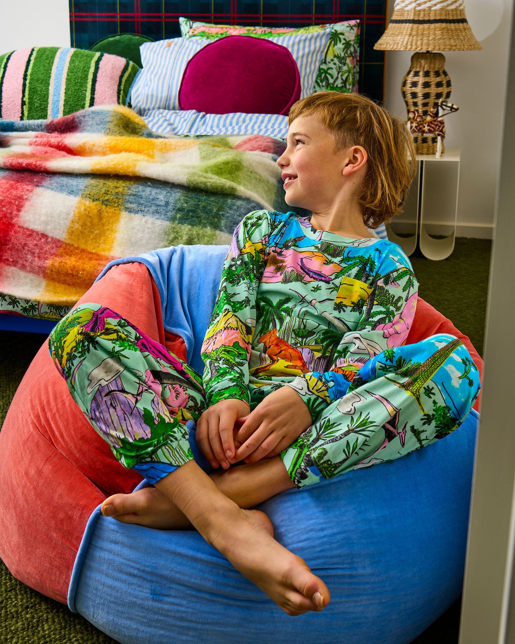 Child sitting cross-legged on Blue Robin beanbag in eclectic bedroom setting