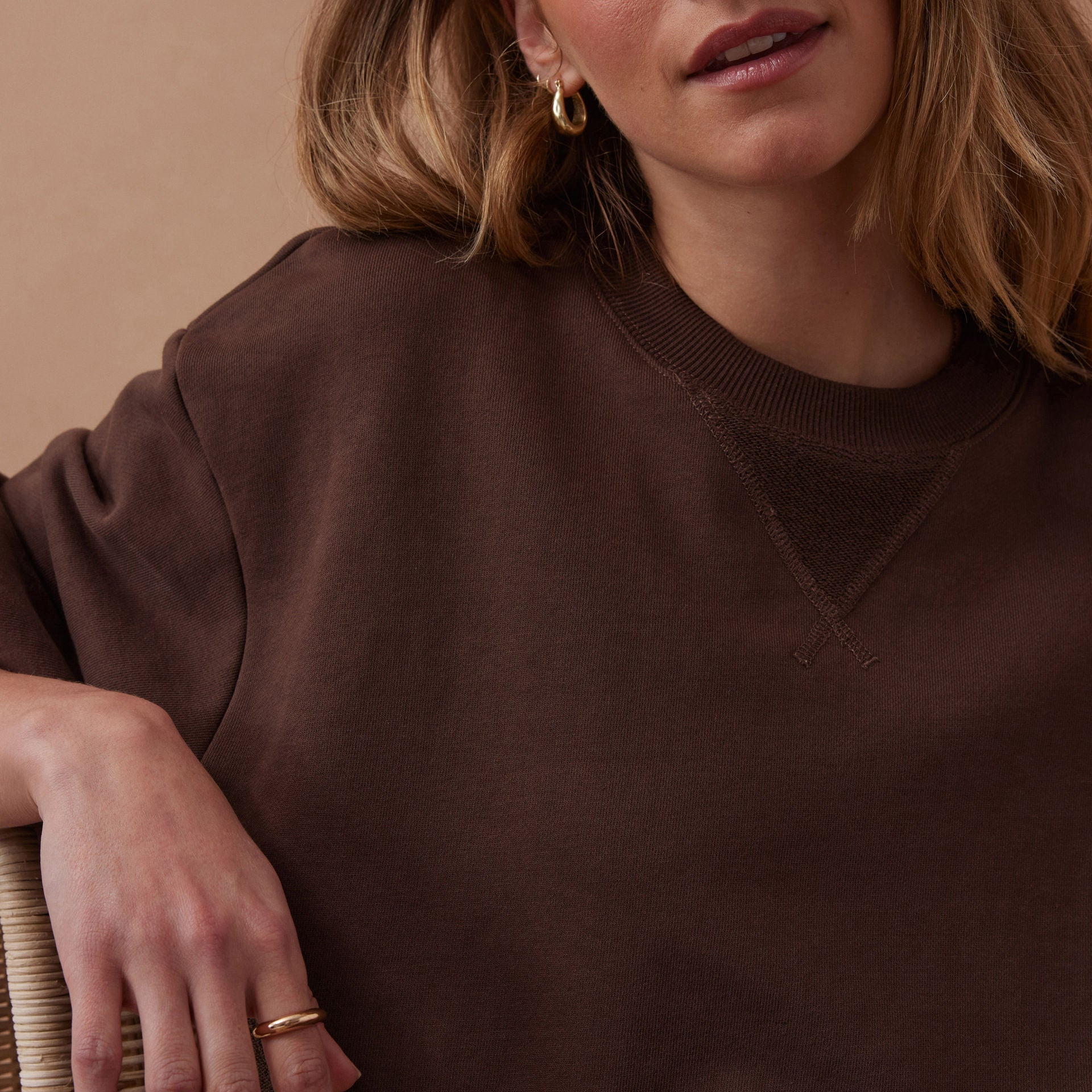 Woman wearing a brown sweater against a beige background