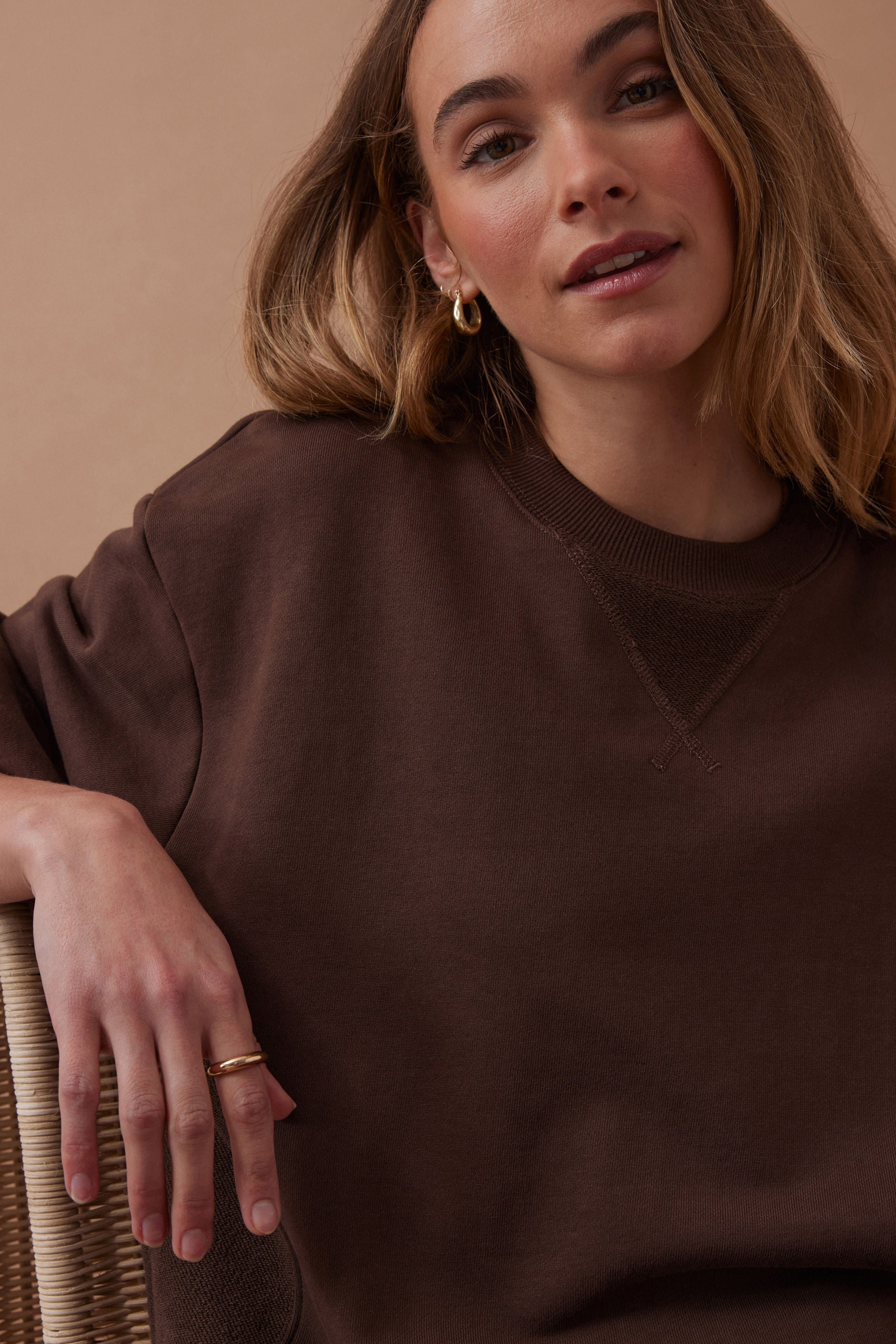 Woman wearing a brown sweater against a beige background