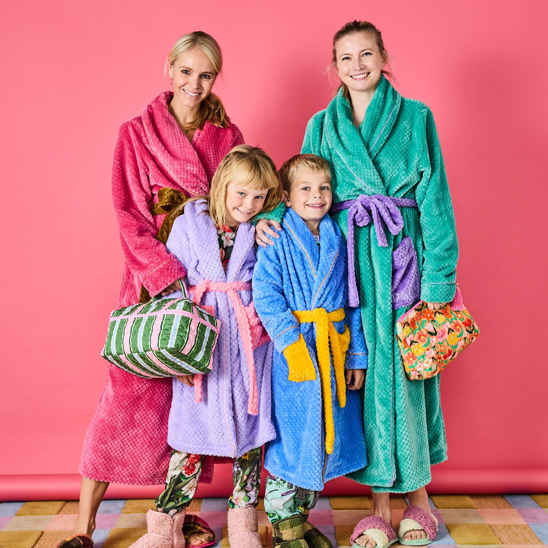 Family lifestyle shot featuring Kip & Co Cactus Stripe Quilted Toiletry Case held by woman in colorful bathrobes