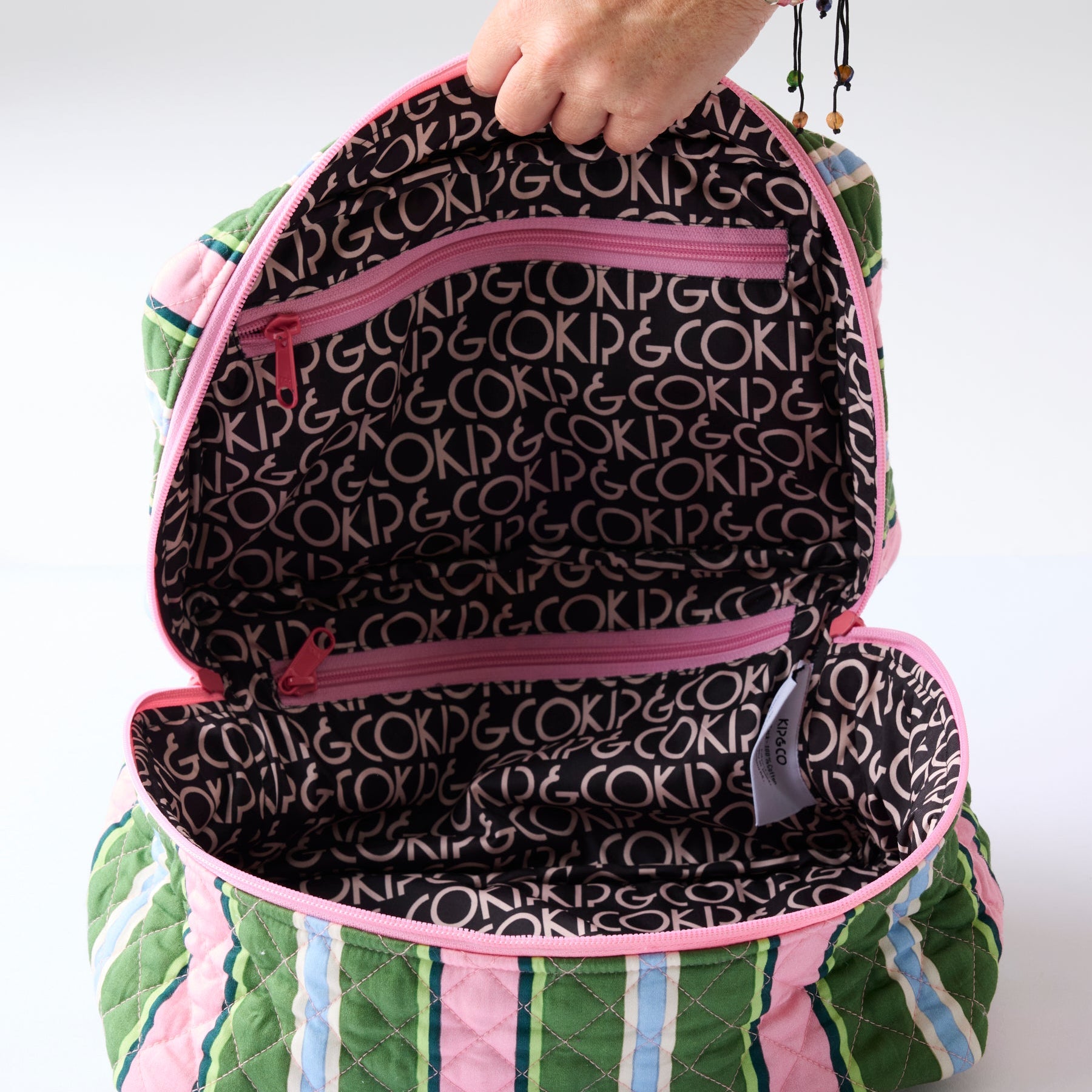 Interior view of Kip & Co Cactus Stripe Toiletry Case showing black logo lining and dual compartment storage