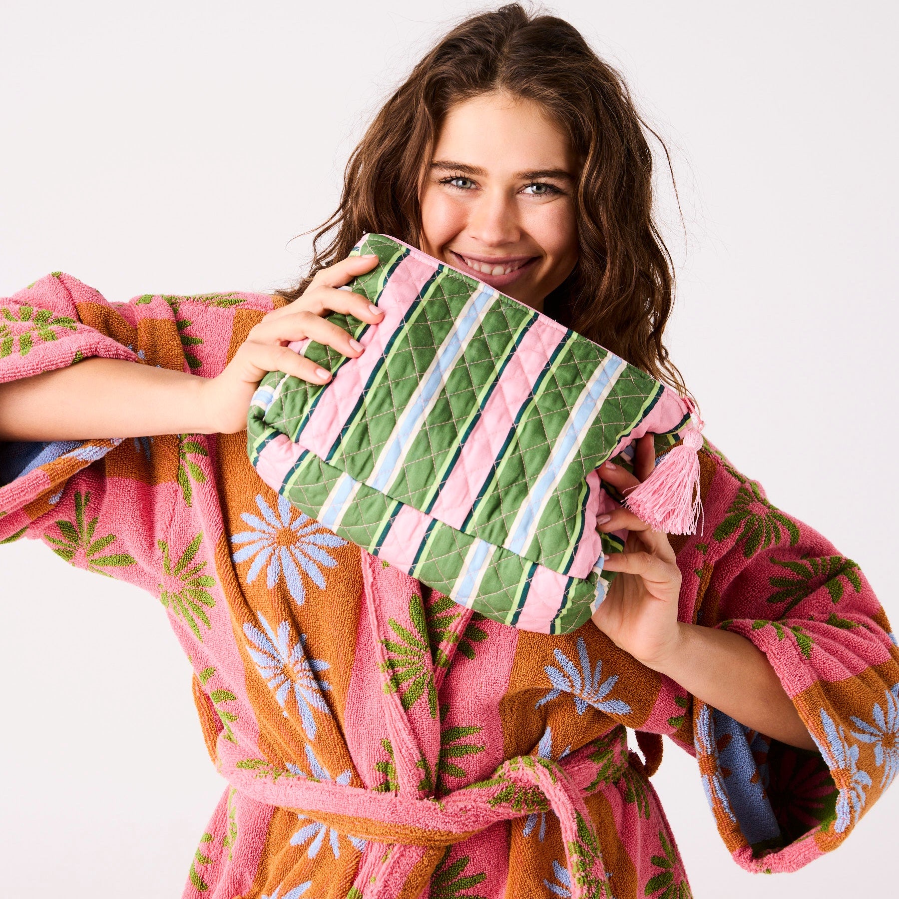 Model holding Cactus Stripe Quilted Cotton Toiletry Purse showing green pink blue striped pattern and pink tassel