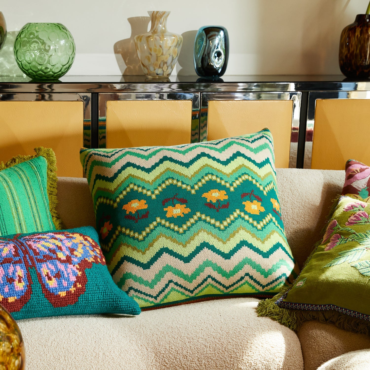 Calina Knit Cushion in Verdant green with zigzag chevron pattern and floral motifs on living room sofa
