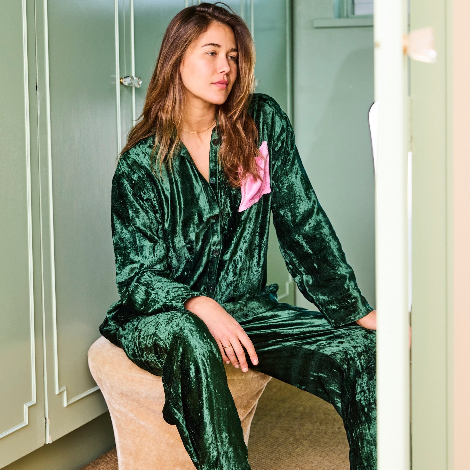 Model sitting wearing Candy Pine Adult Velvet Long Sleeve Shirt and Pant Pyjama Set by Kip Co in green