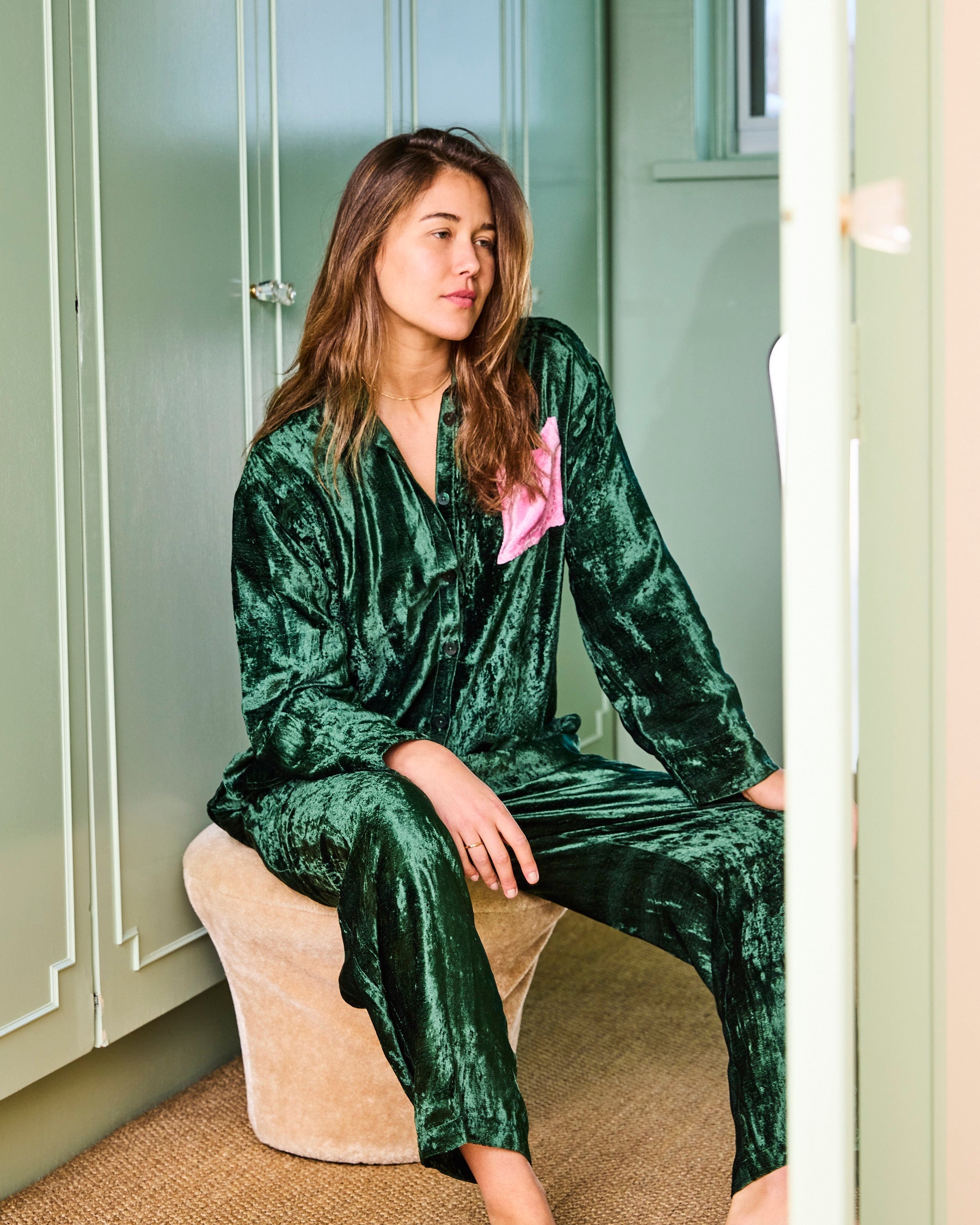 Model sitting wearing Candy Pine Adult Velvet Long Sleeve Shirt and Pant Pyjama Set by Kip Co in green