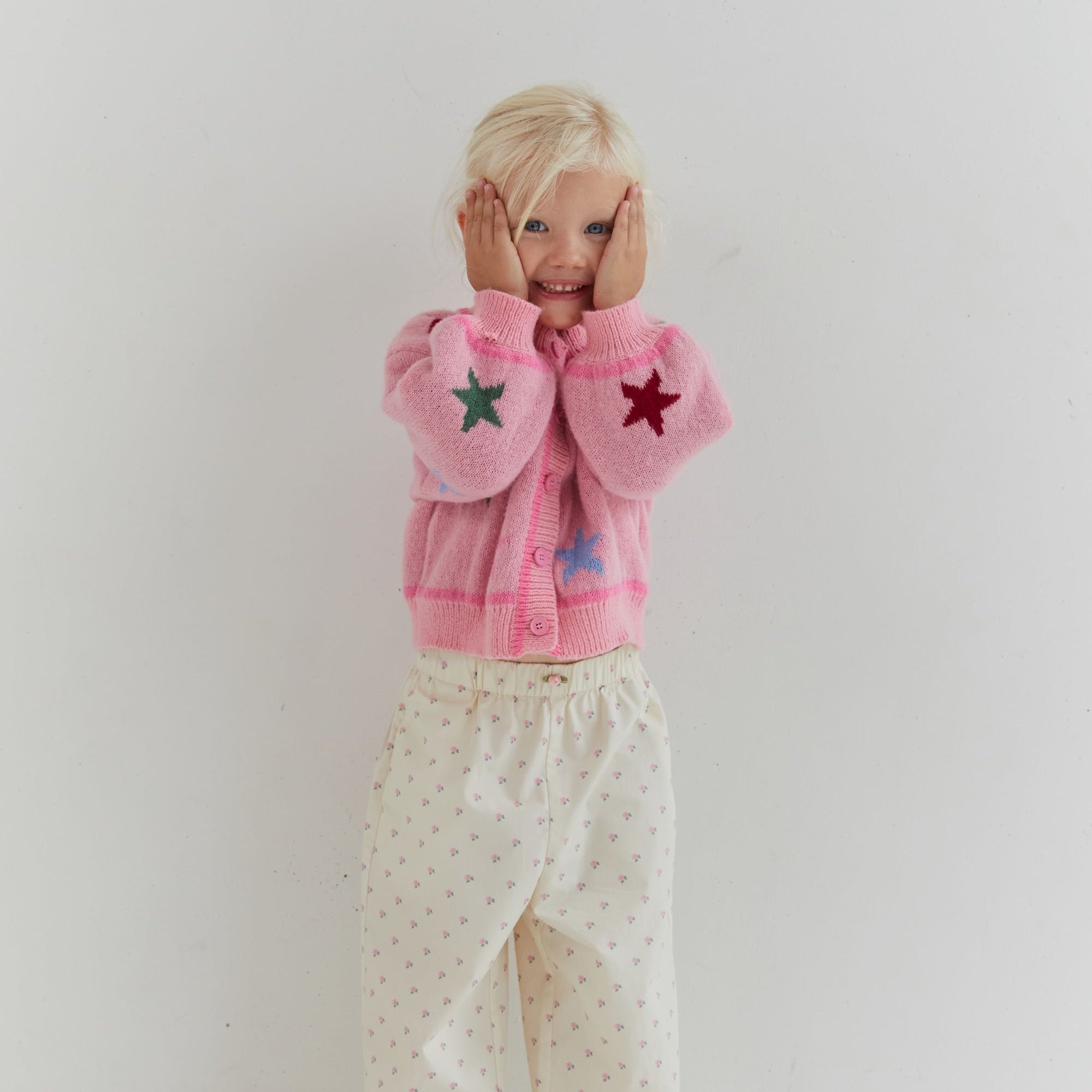 Front view of child wearing Cleo Pant with rose pattern and ruffle hem detail