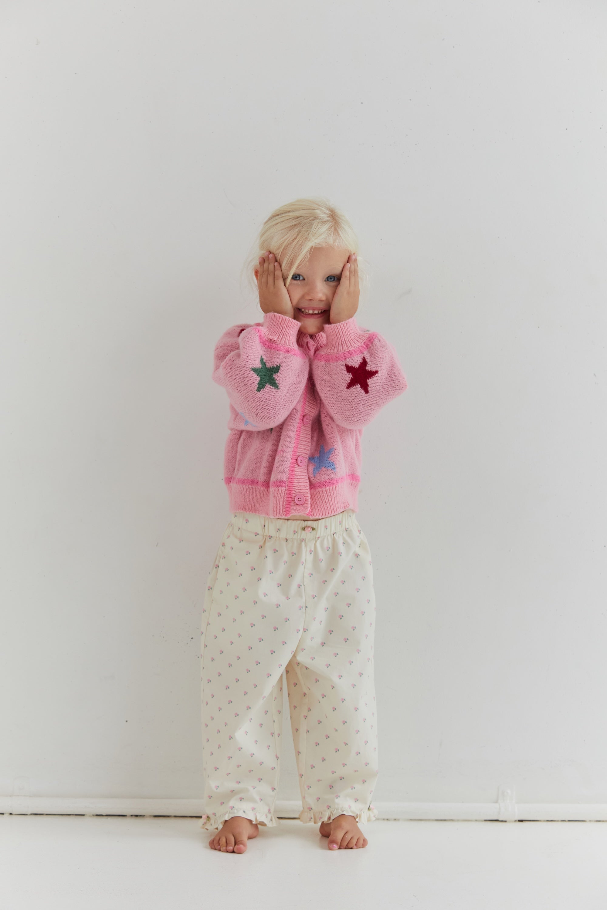 Front view of child wearing Cleo Pant with rose pattern and ruffle hem detail