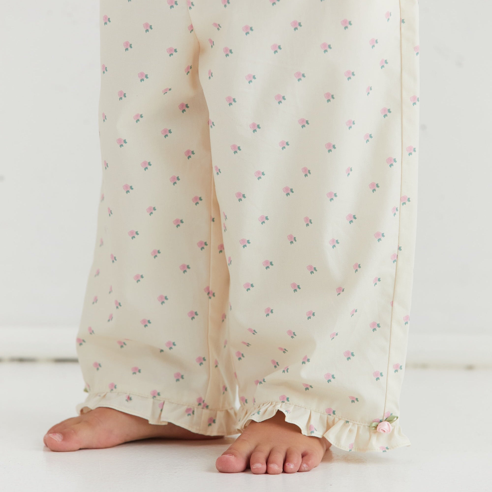 Close-up of Cleo Pant rose pattern fabric and ruffle hem detail from front view