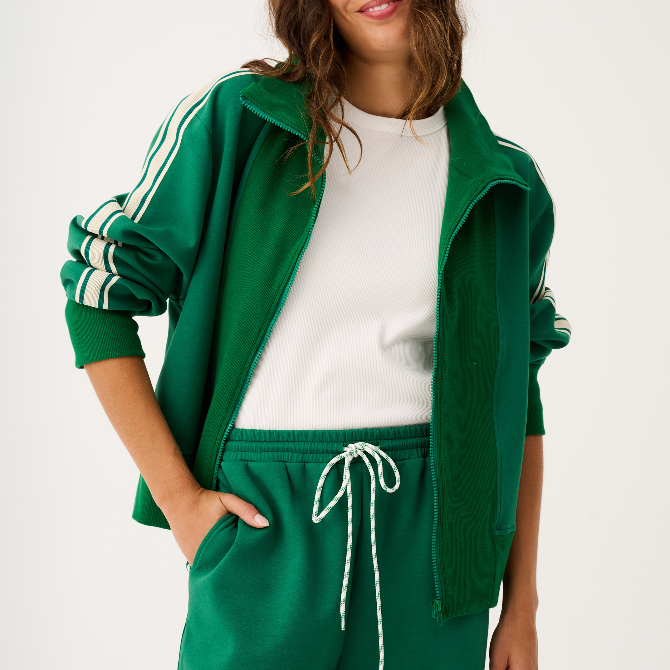 Close-up front view of green zip through sweater showing full zipper closure and striped sleeve details