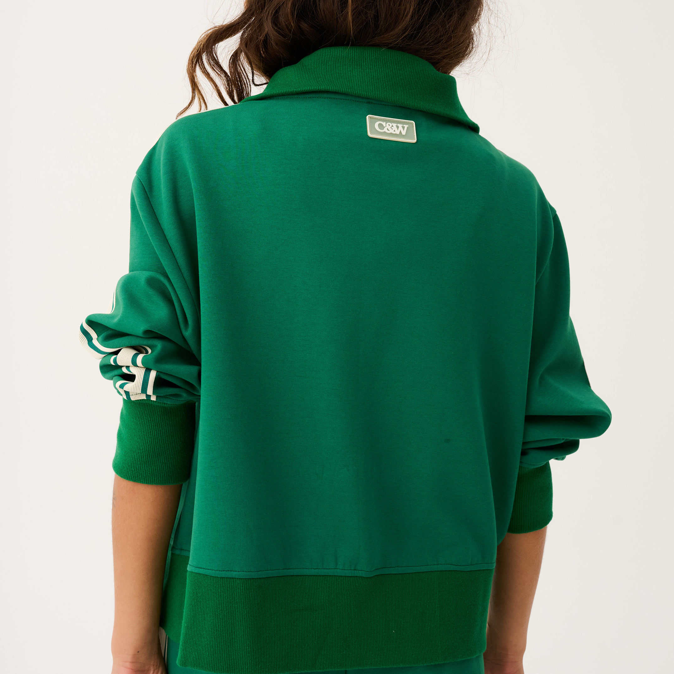 Back view of green Corey sweater displaying brand label and white striped sleeve design