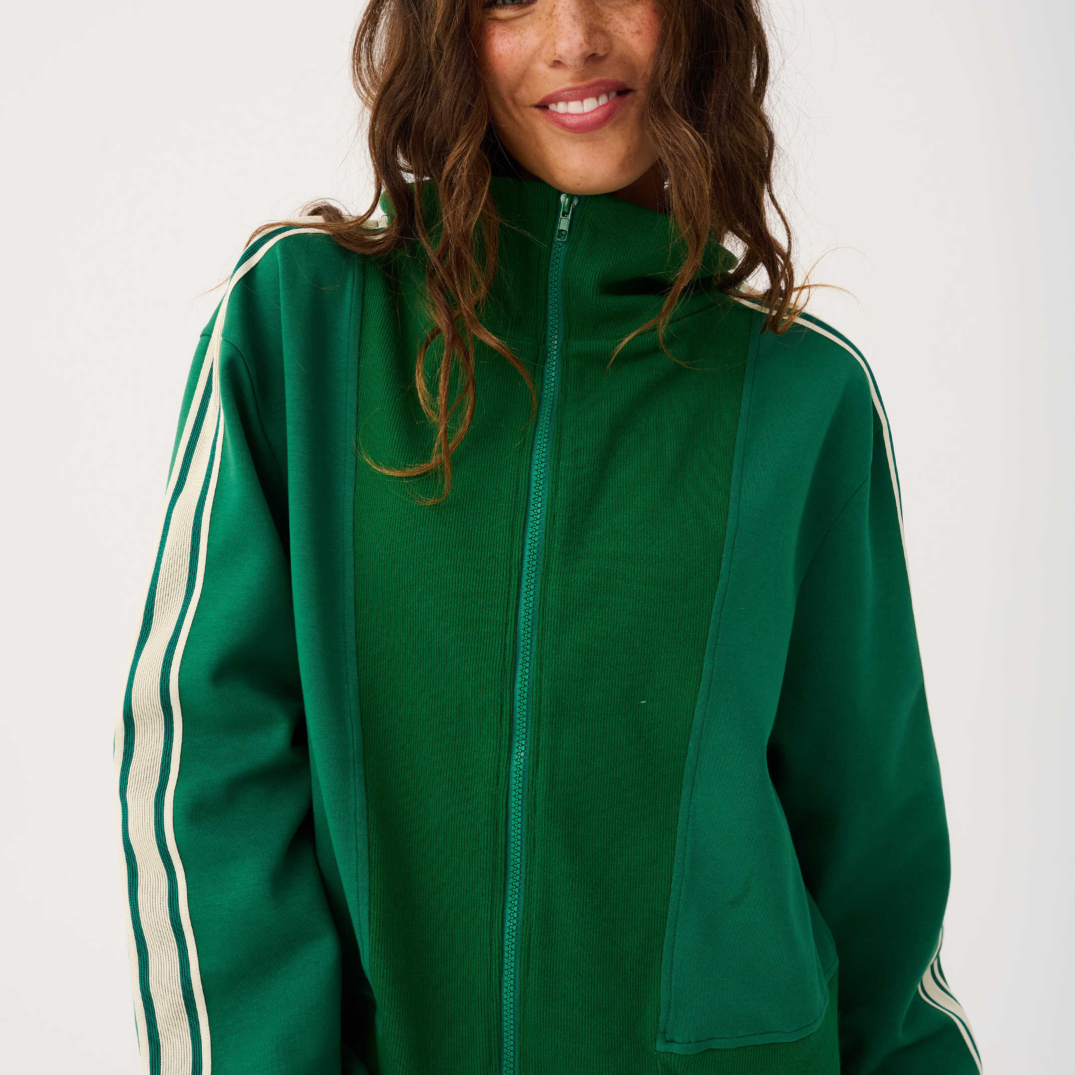 Front detail of green zip up sweater with high collar showing zipper pull and ribbed cuffs