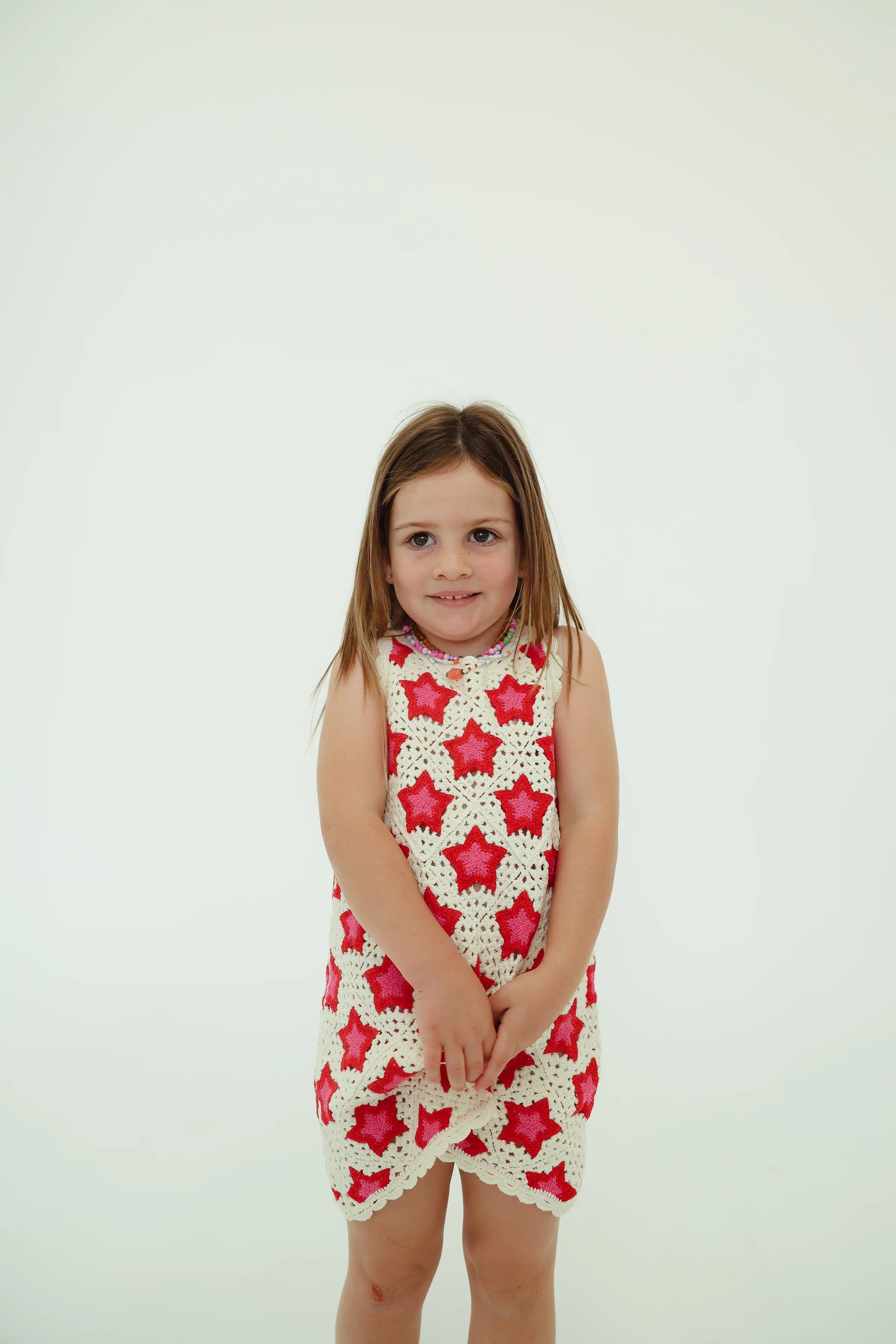 girl wearing cotton crochet dress with pink and red stars