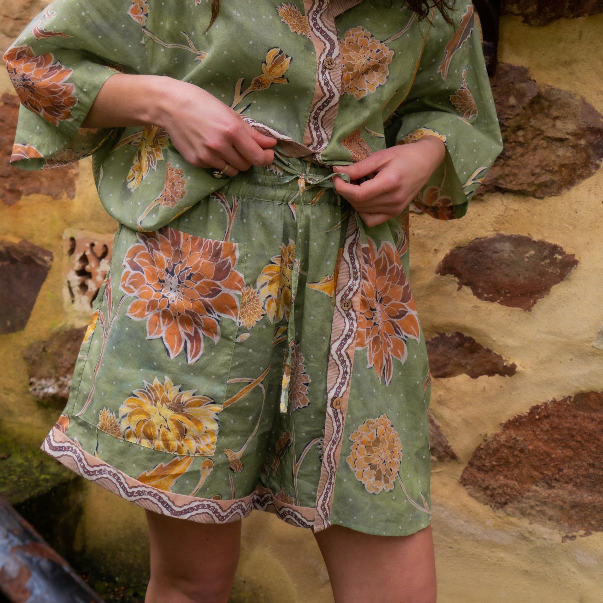 Close-up detail of drawstring waist and hand-painted dahlia floral pattern on organic cotton shorts