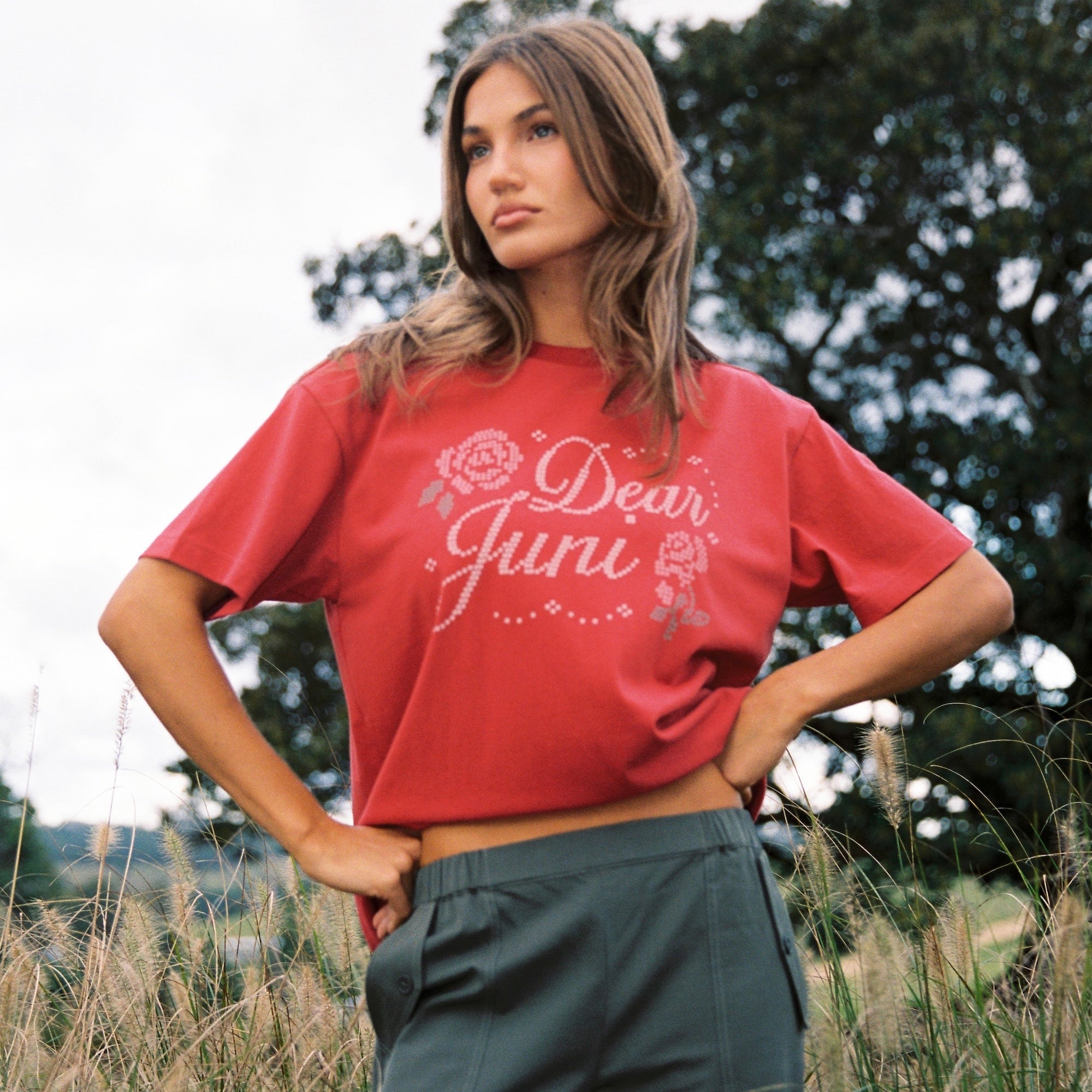 Side angle of red Dear Juni Tee displaying rhinestone embellished lettering and floral motifs