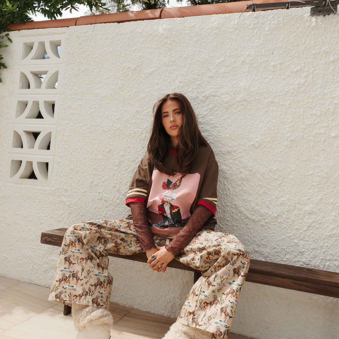 Model sitting wearing Deserted Pant showcasing western cowboy print pattern and comfortable loose fit styling