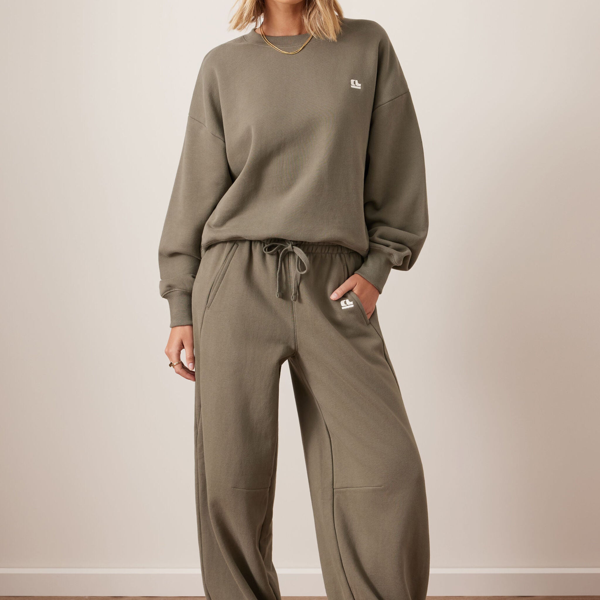 Full outfit view of washed olive barrel trackpants with matching sweatshirt and sneakers