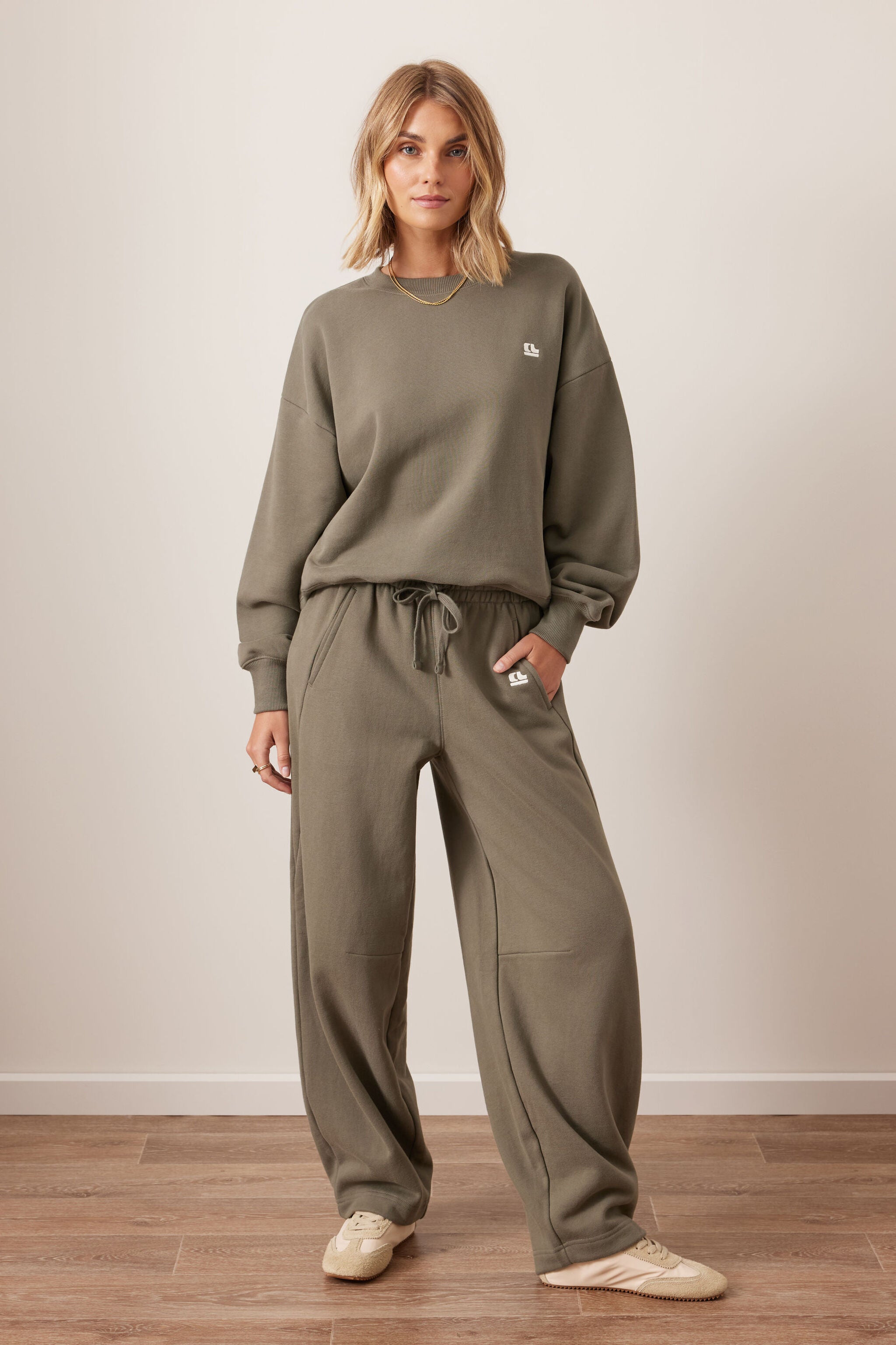 Full outfit view of washed olive barrel trackpants with matching sweatshirt and sneakers
