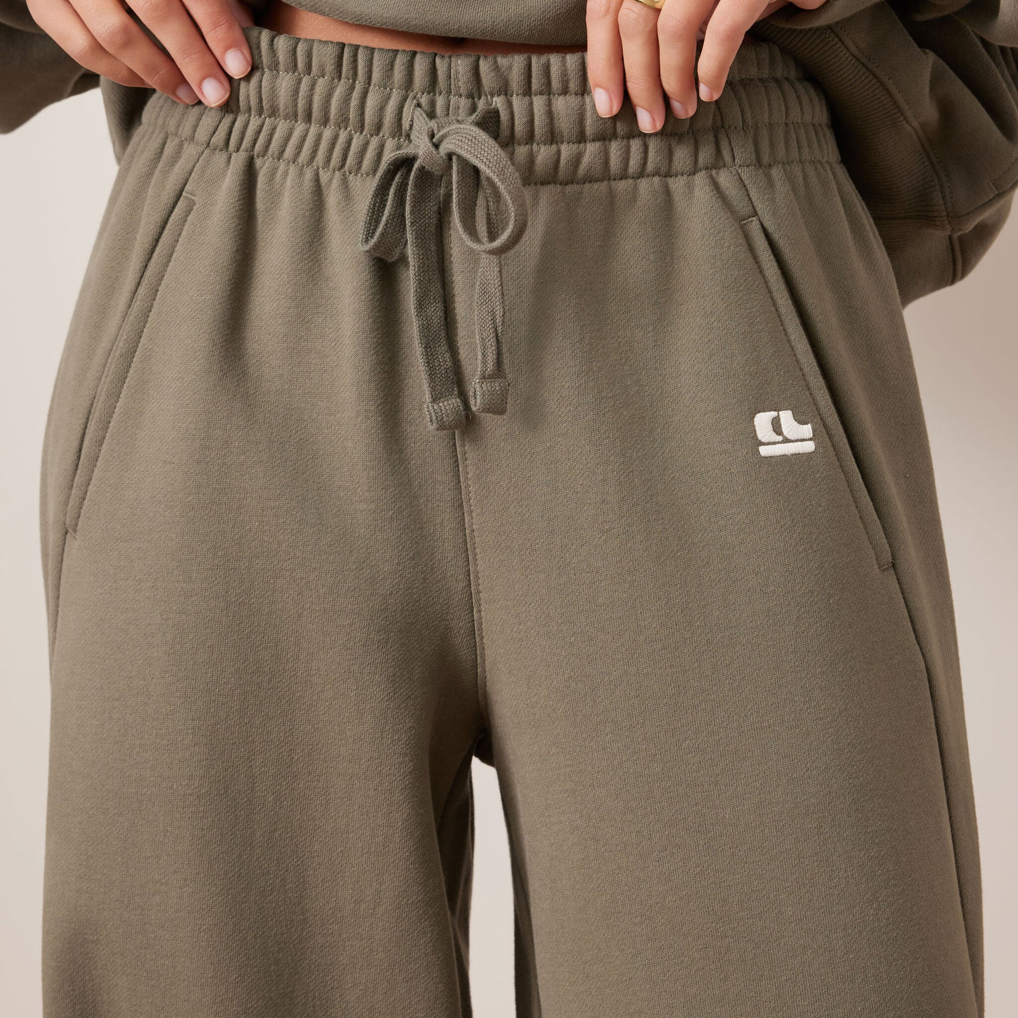 Close-up detail of elastic waistband and drawstring on washed olive barrel trackpants