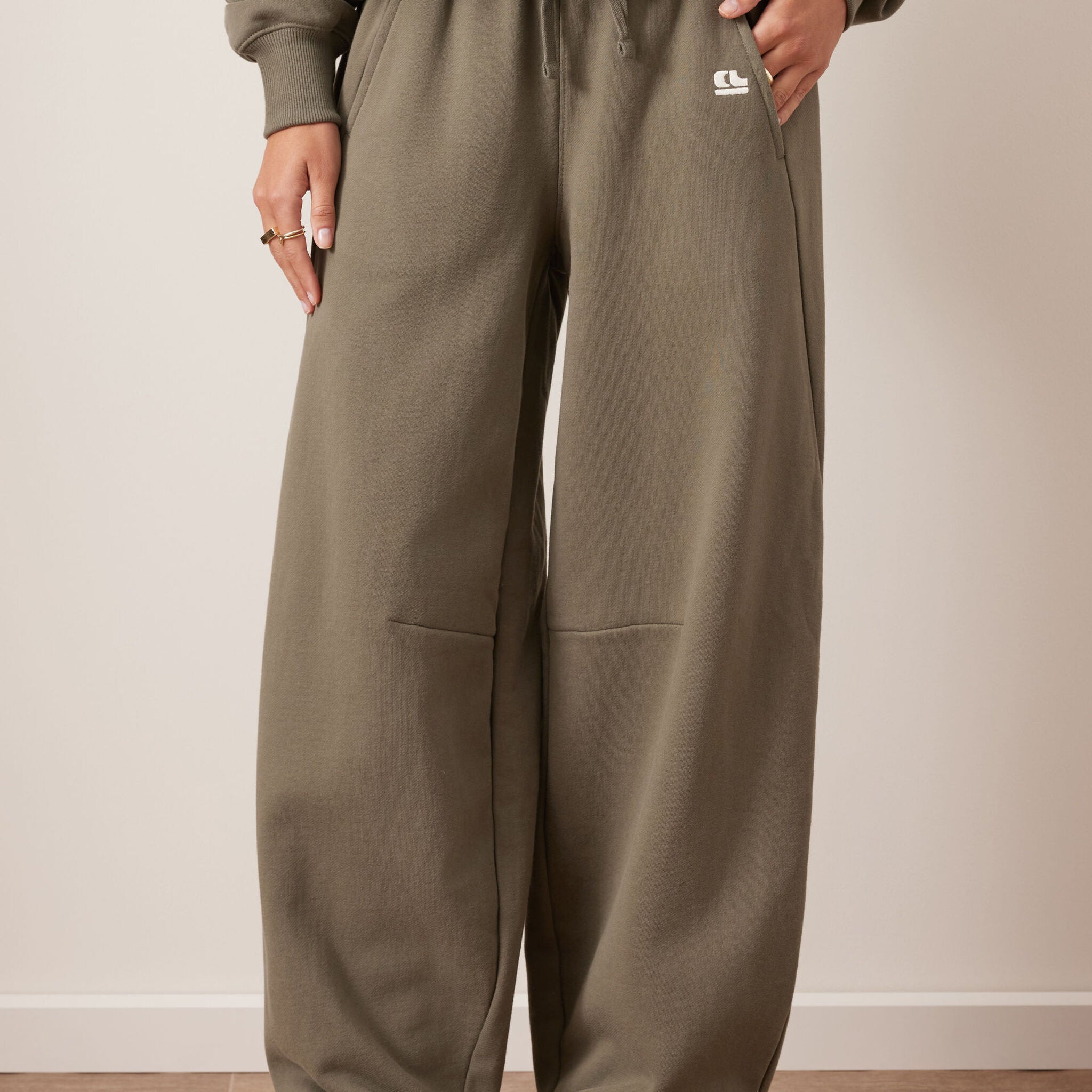 Front view of washed olive barrel trackpants with wide leg silhouette and side pockets