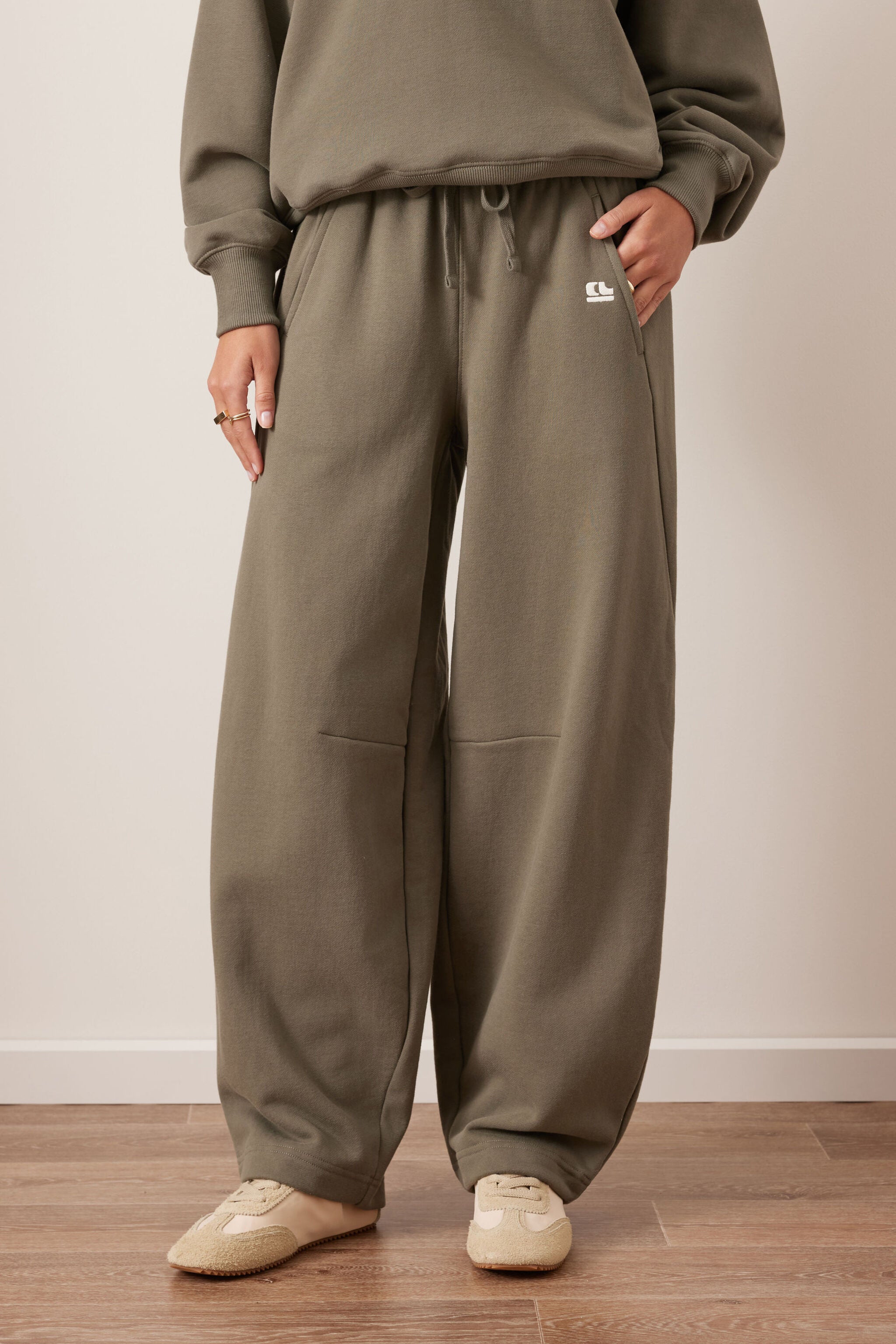 Front view of washed olive barrel trackpants with wide leg silhouette and side pockets