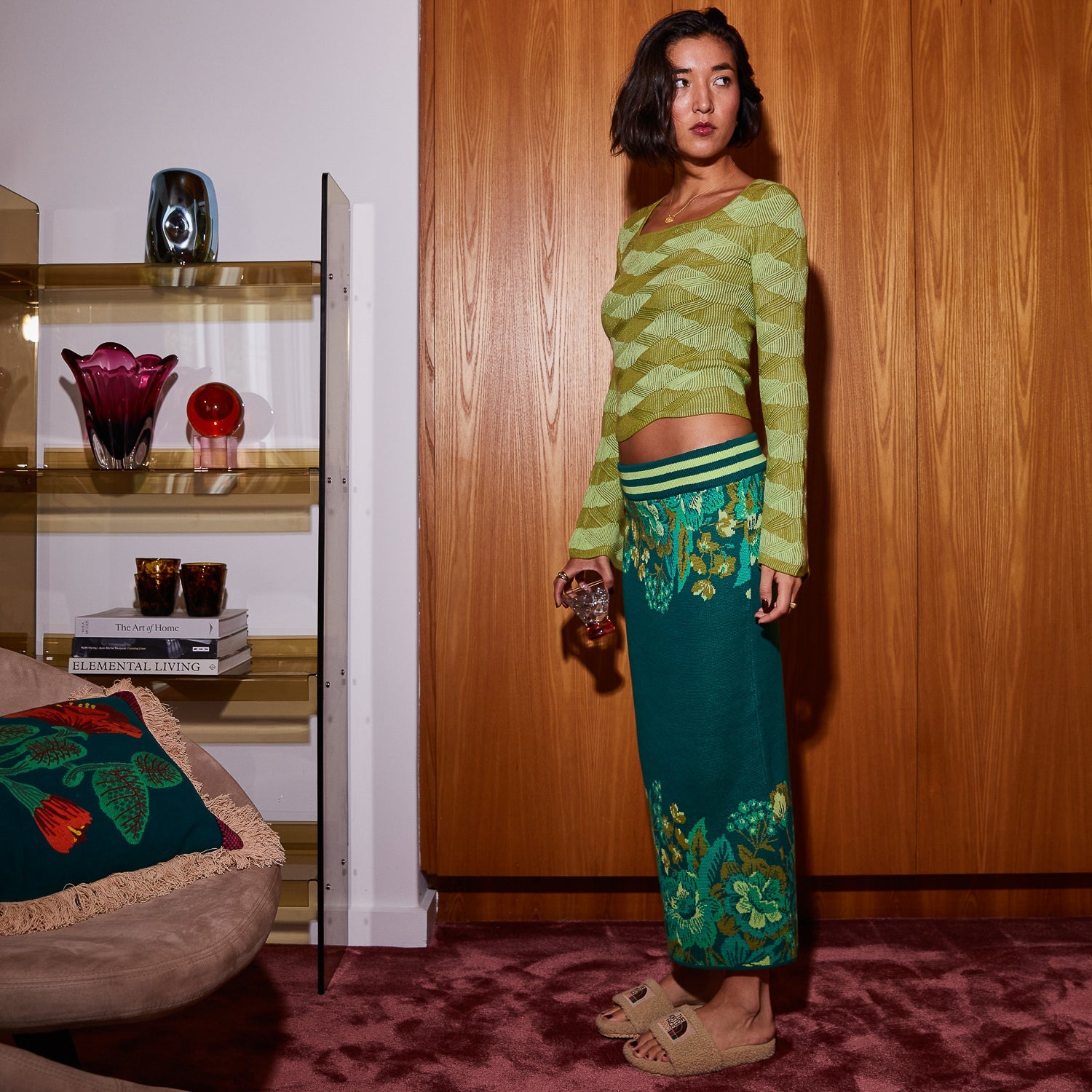 Model wearing Sage Clare Eliza Knit Maxi Skirt in teal with green floral print in modern living room