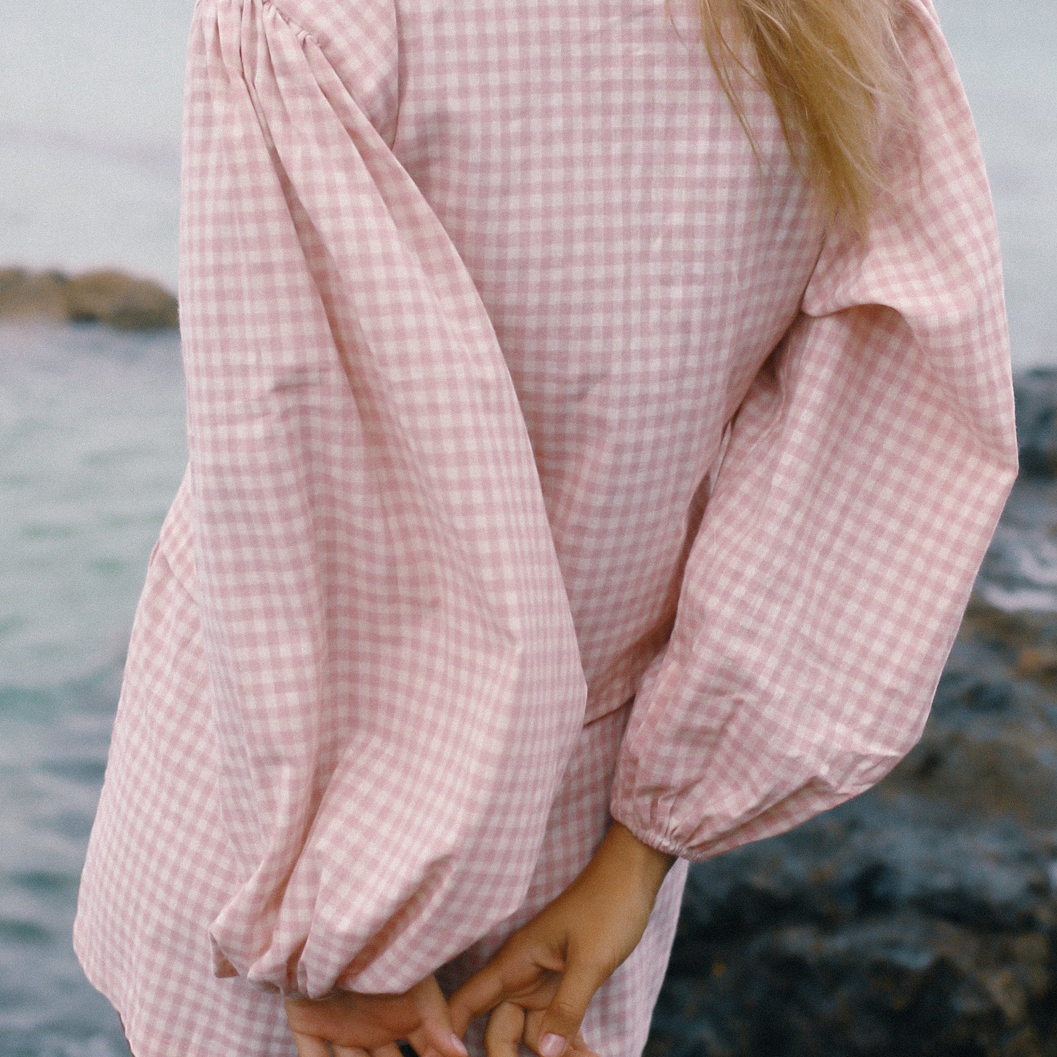 Person wearing a pink checkered long sleeve shirt by the water - Ella Wrap Top pink gingham by The Bare Road