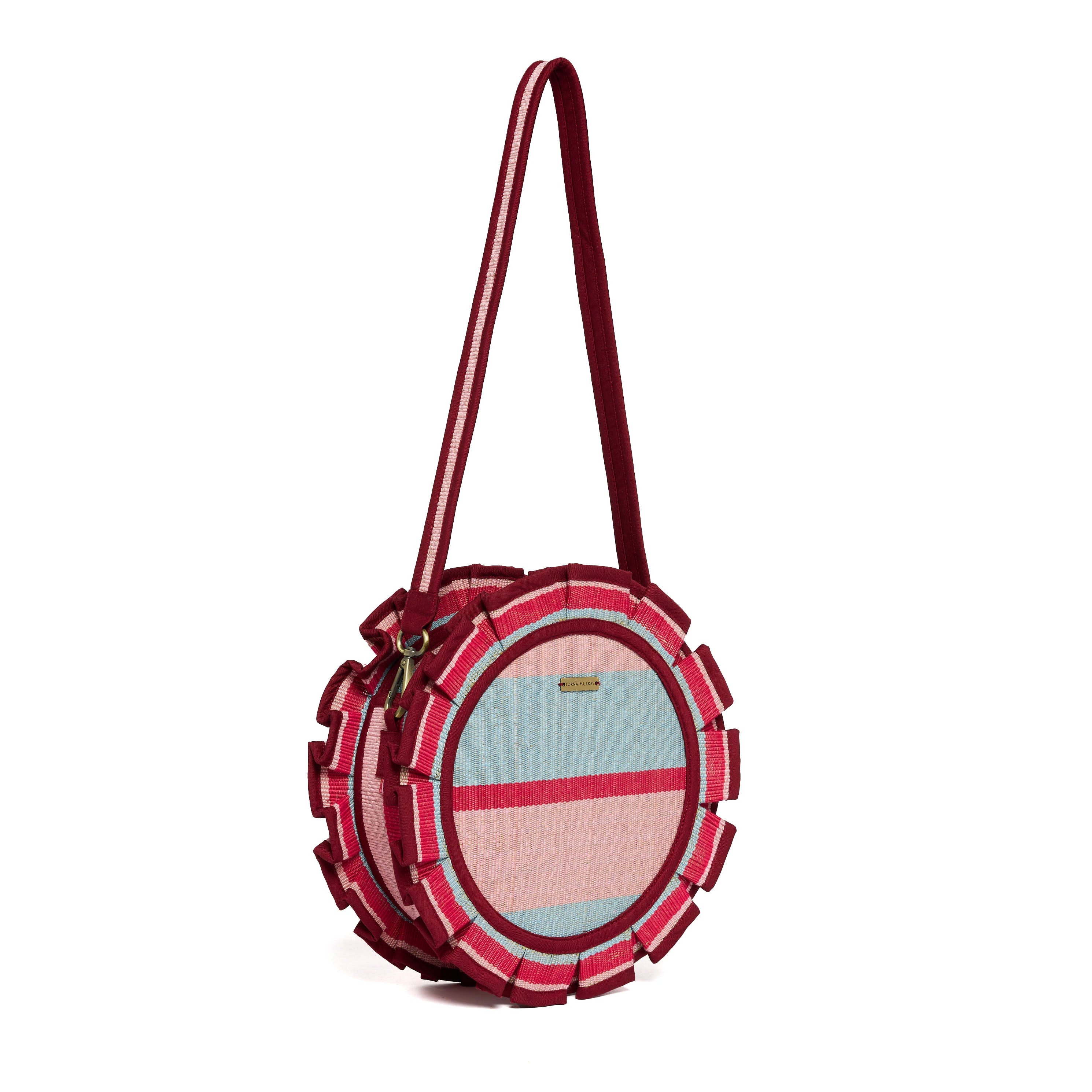 Side angle view of Escape Mini Love Note Tote showing circular shape with striped pattern and burgundy shoulder strap