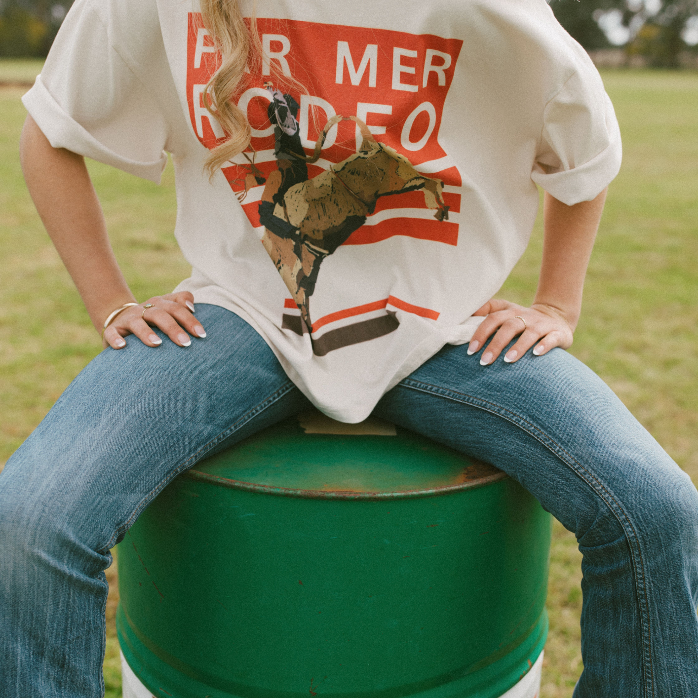 Close-up front view of Rodeo Box Tee displaying orange striped background with rodeo bull rider print