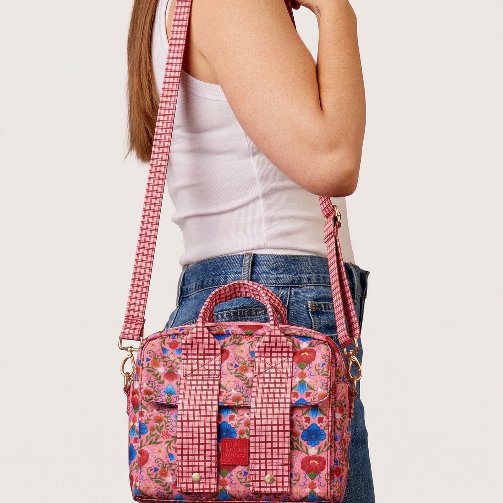 Fable lunch tote worn crossbody with pink floral print and red gingham shoulder strap