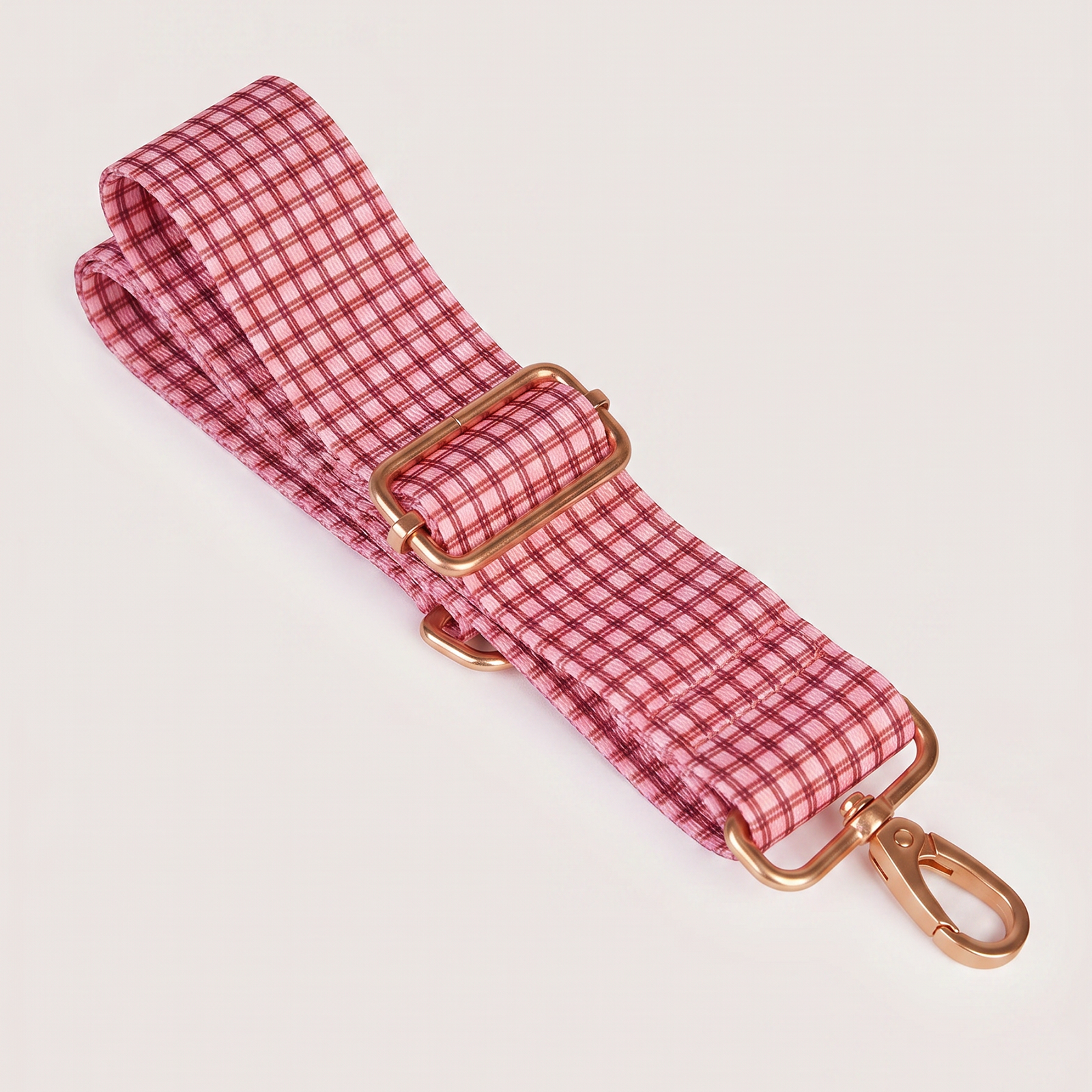 Close-up of red gingham adjustable shoulder strap with gold hardware buckle and clip