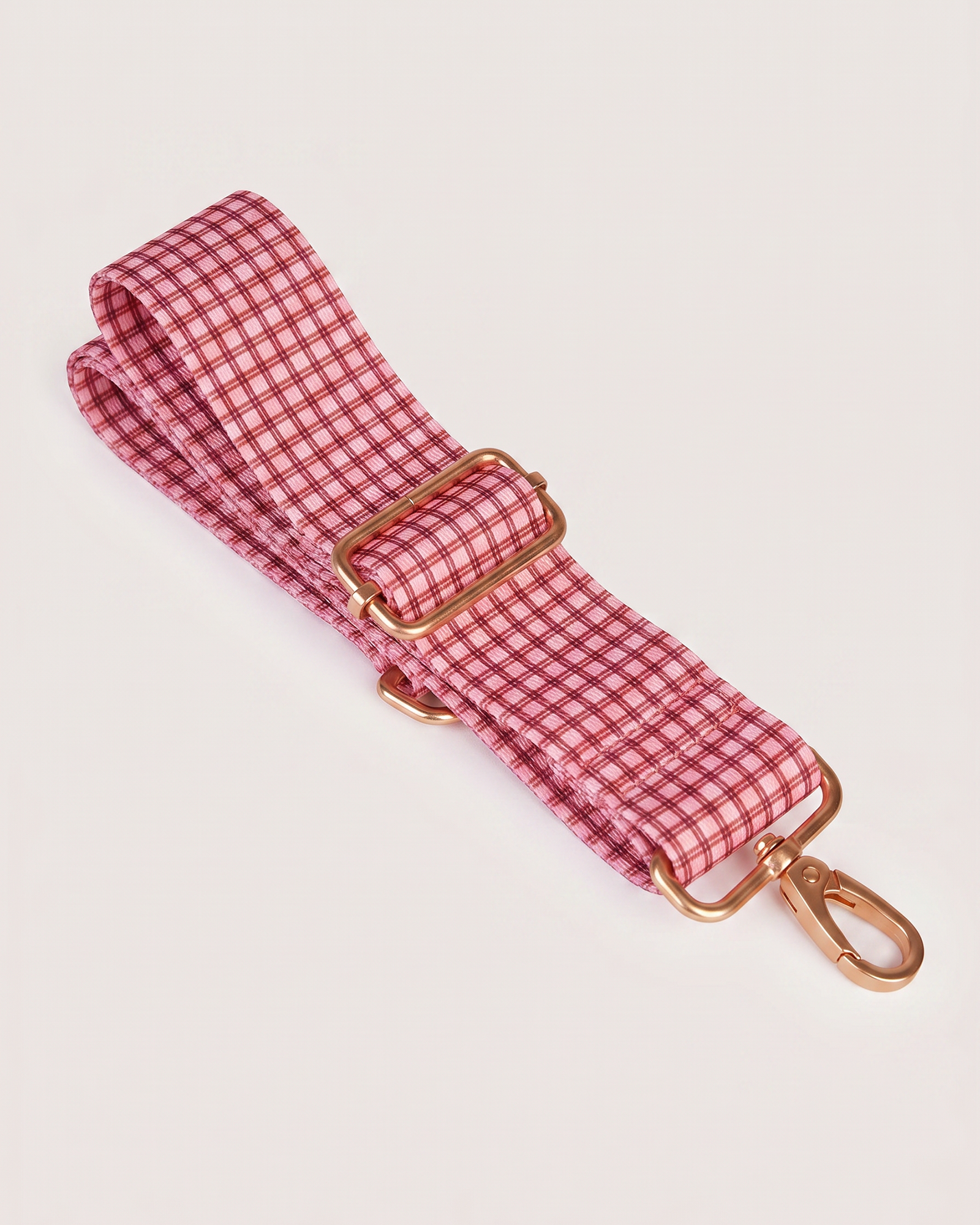 Close-up of red gingham adjustable shoulder strap with gold hardware buckle and clip