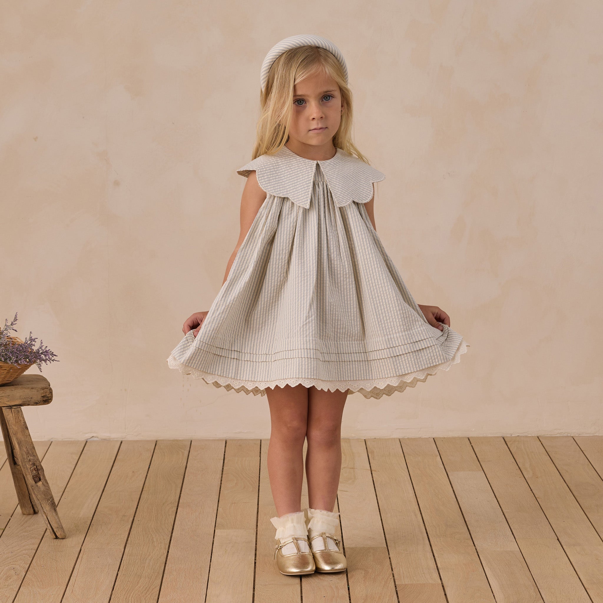 Young girl wearing Florence Dress in sky stripe showing full front view with pleated skirt