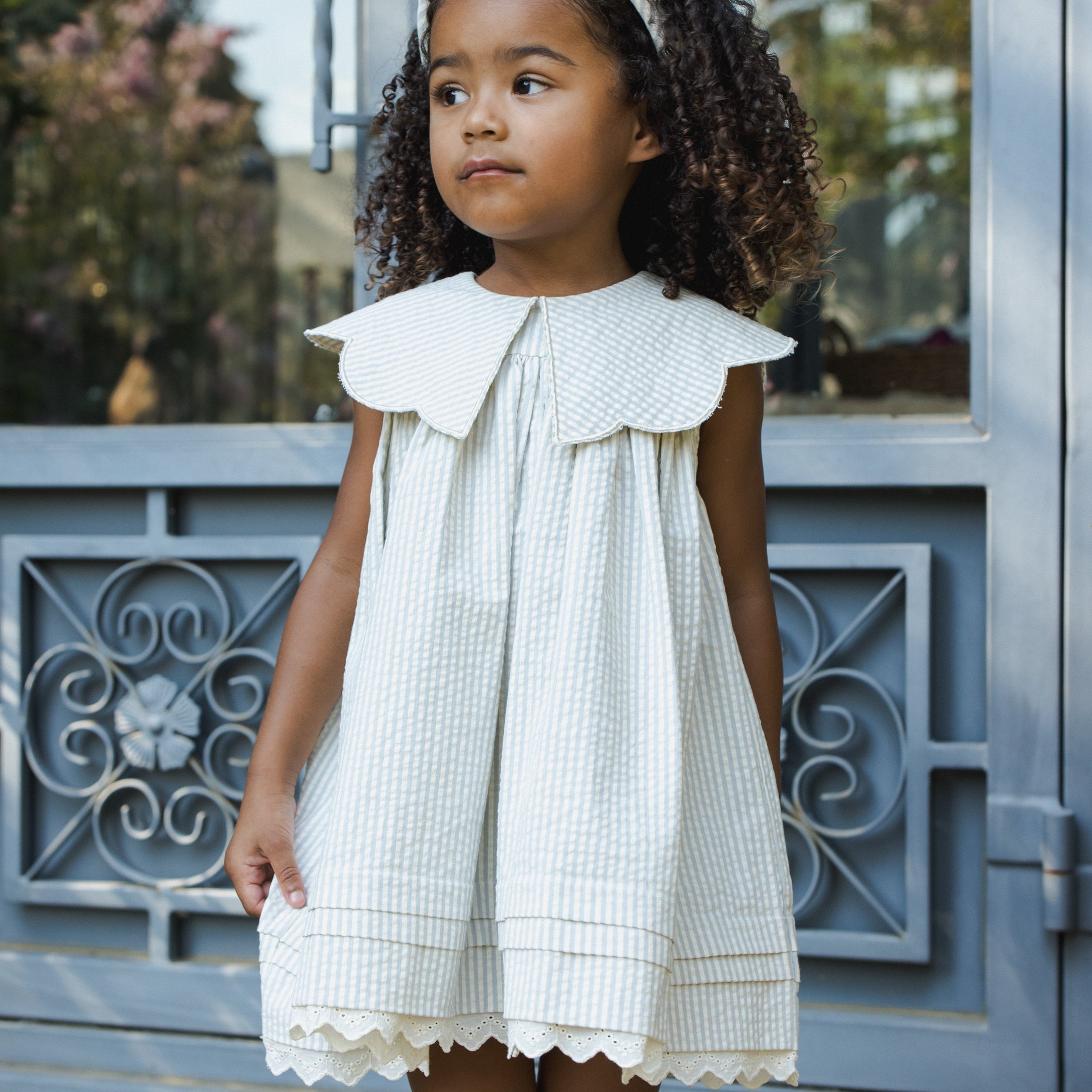 Child modeling Florence Dress Sky Stripe outdoors showing eyelet hem detail
