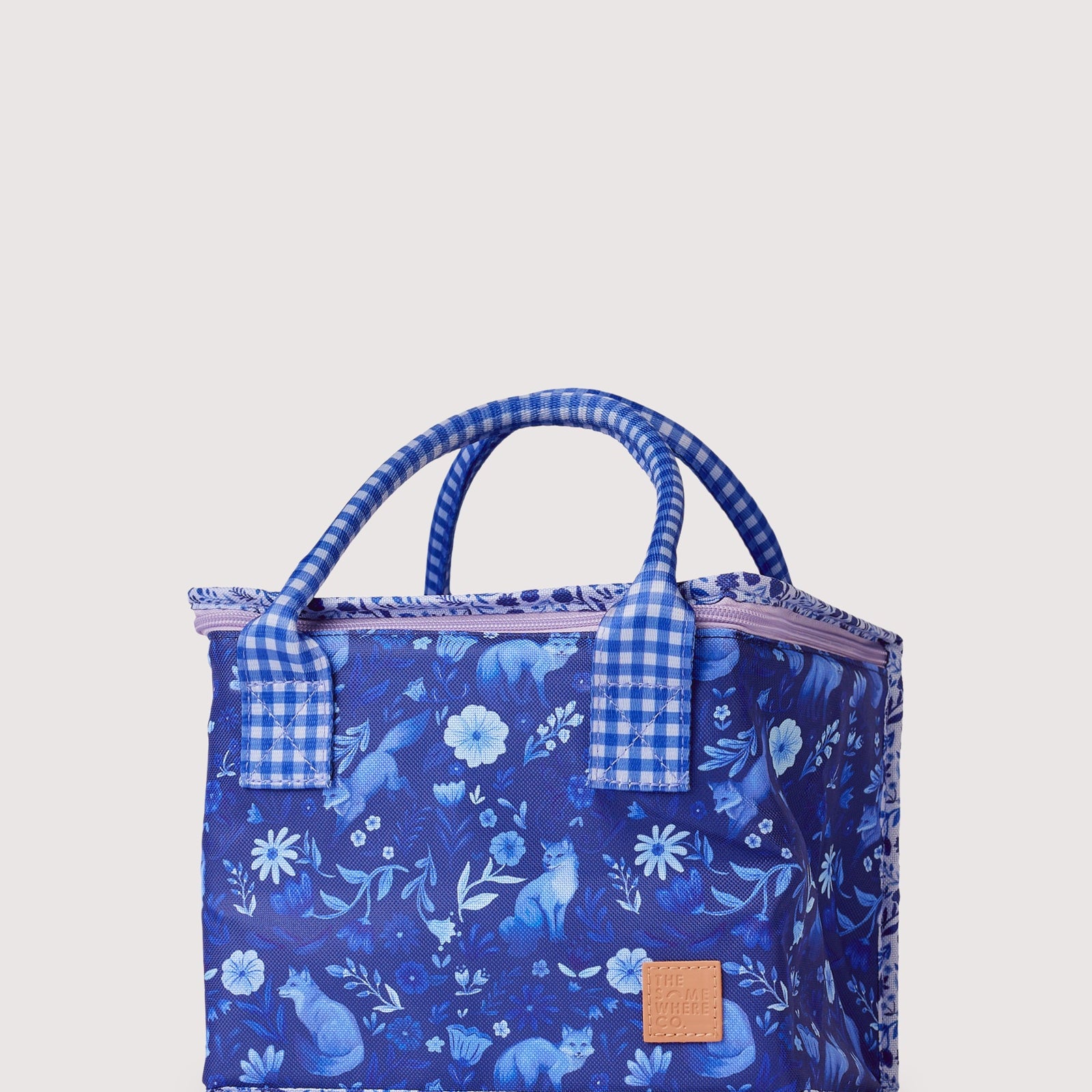 Front view of blue floral lunch bag with gingham trim handles and leather logo patch