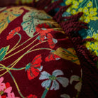 Close-up of embroidered fabric with floral patterns on a dark background - velvet floral Genevieve Fringe Cushion by Sage & Clare