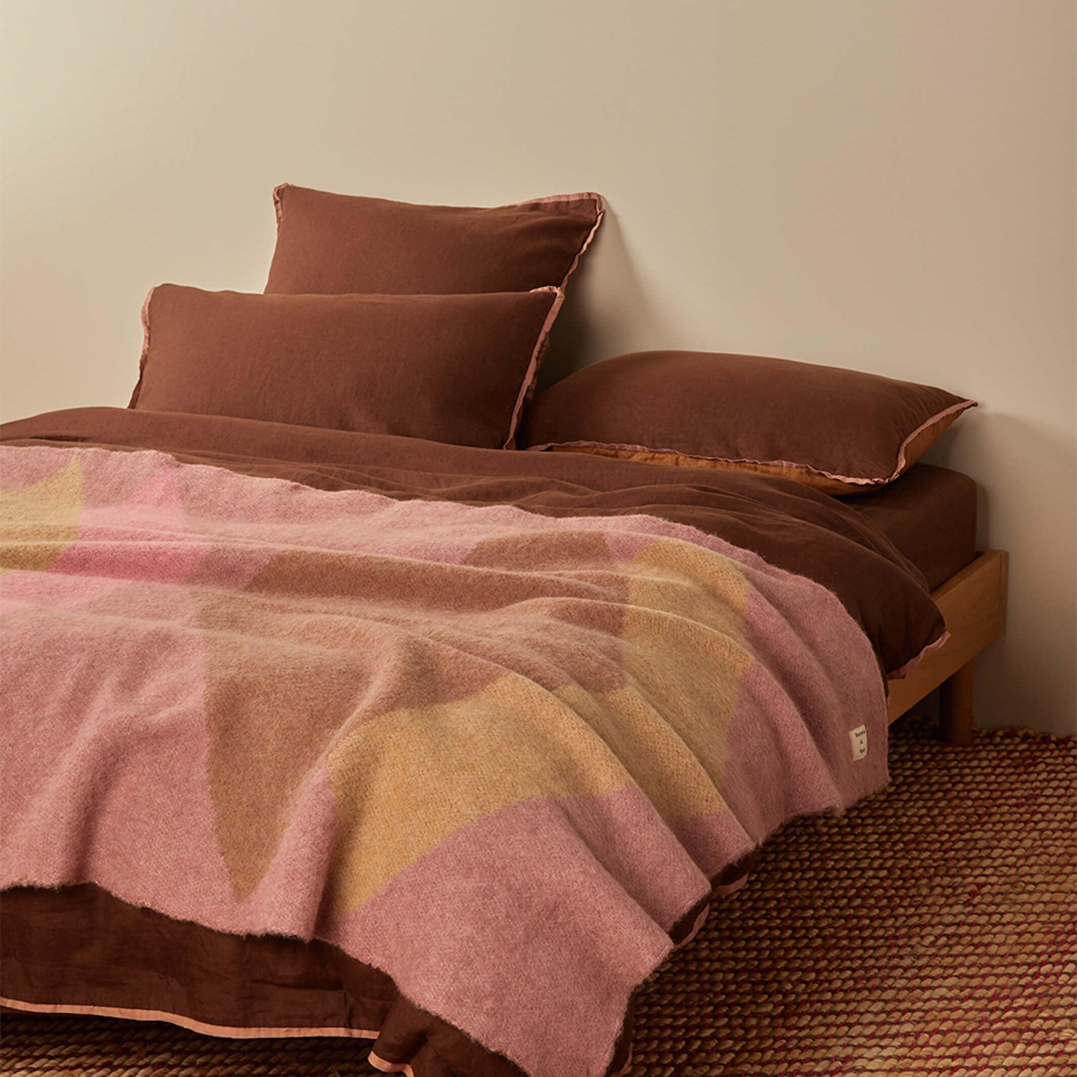 Close-up of Geometric Pink Mohair Throw showing diagonal color block pattern on bed